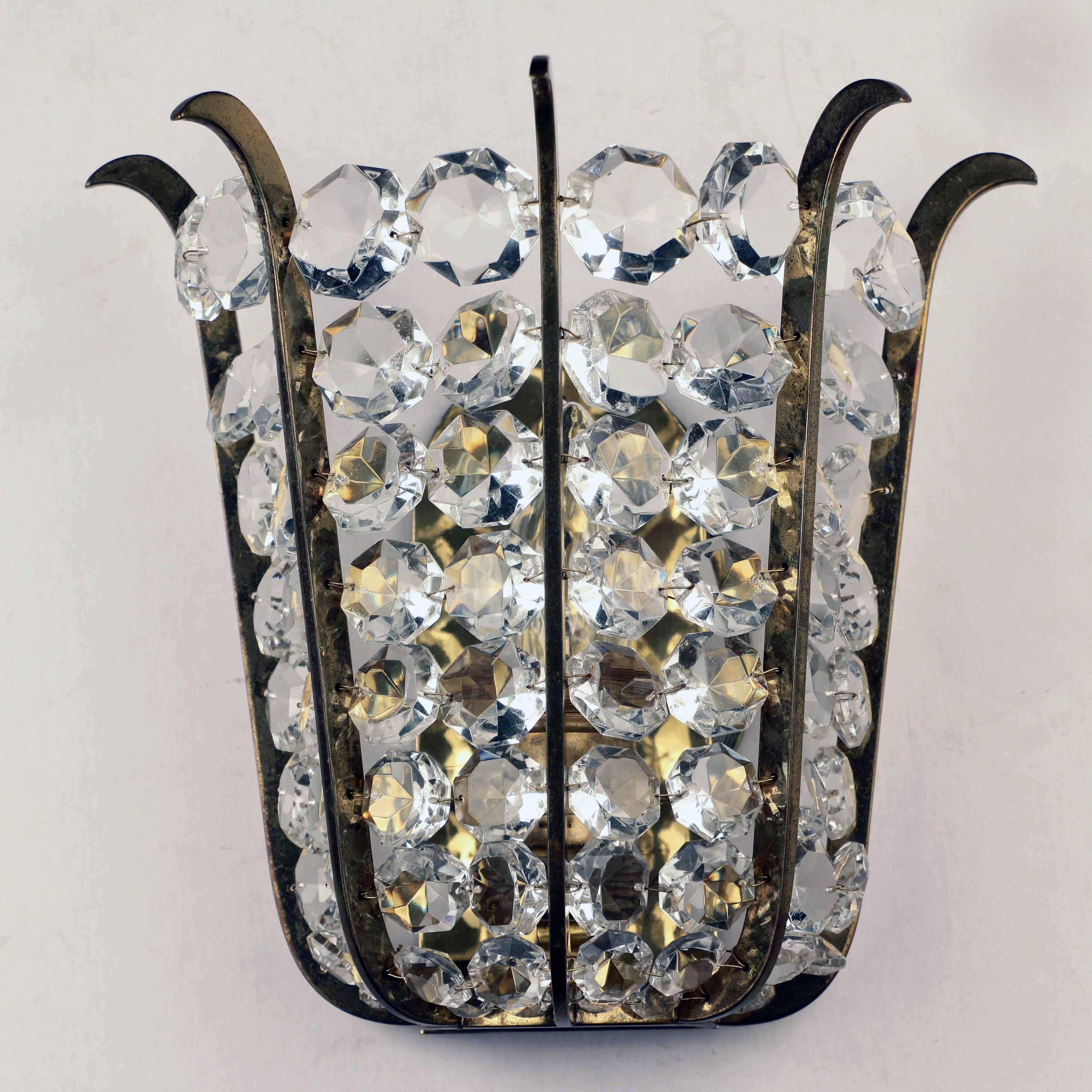 This set dates from the 1950s and is full of subtle quality. Each sconce tapers slightly from top to bottom and is set with graduated octagonal jewel-cut lead crystals. The glass is unusually brilliant and the shaped brass separations are gold