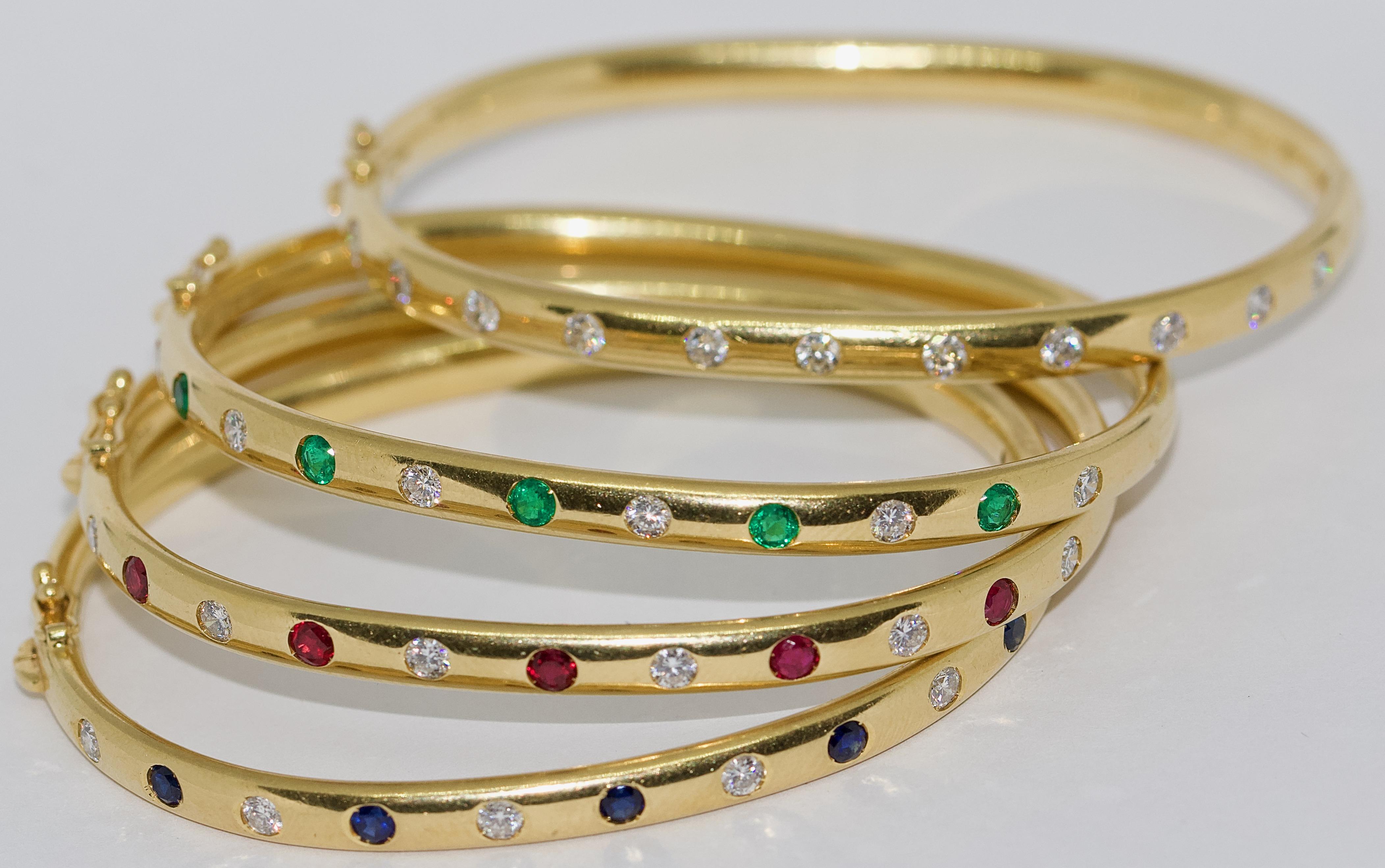 Set of four modern, charming bangles in 18 Karat gold set with diamonds, sapphires and emeralds.

Finest goldsmith work. Each bracelet is hallmarked.
All 44 stones are of very good quality.
Each gemstone weighs about 0.1 carat.

Excellent condition.