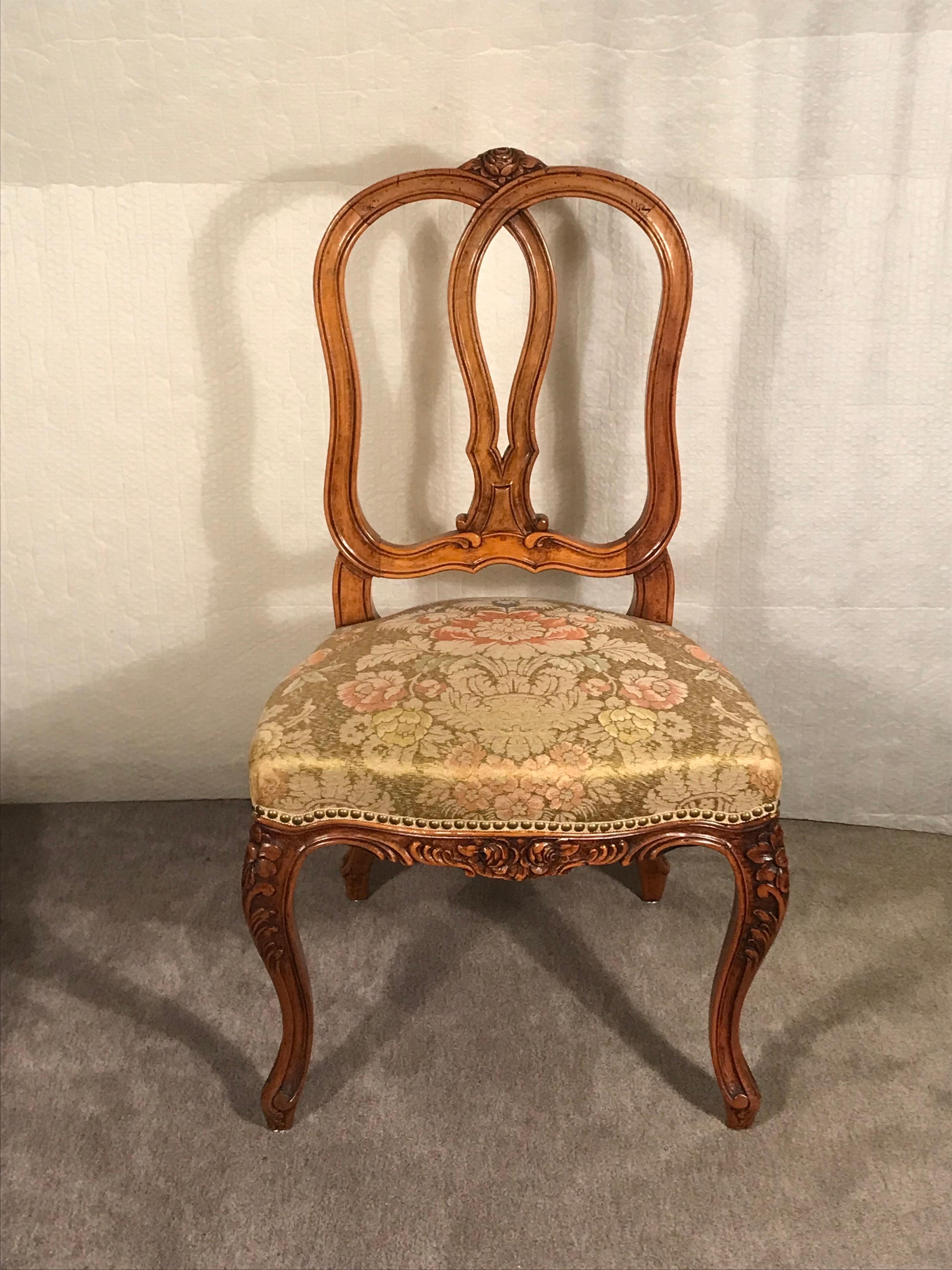 This set of four Baroque Style chairs have a beautifully hand-carved flower and rocaille decor. The chairs date back to the 19th century and were made around 1860-70. They are in original condition and have been covered with a floral brocade fabric. 