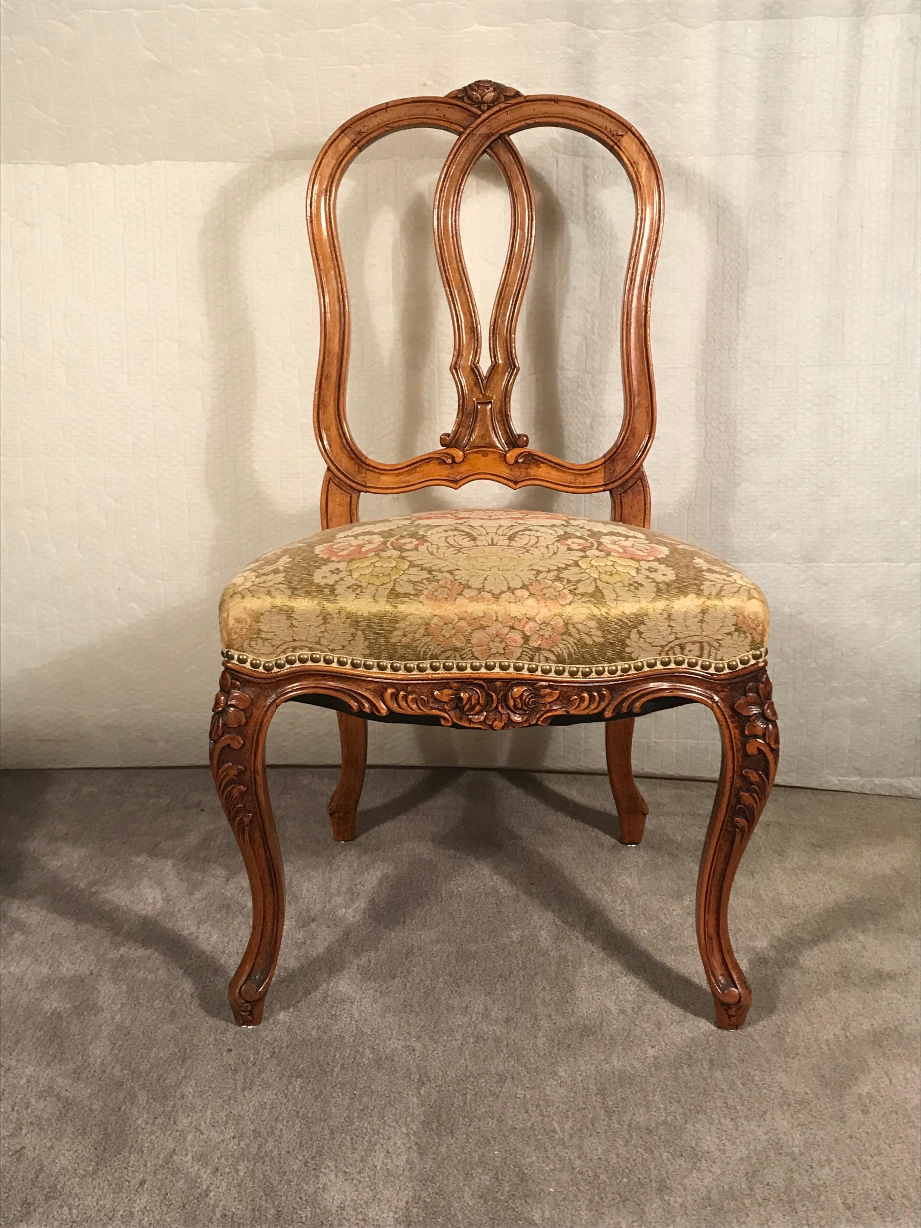 This set of four Baroque style chairs have a beautifully hand-carved flower and rocaille decor. The chairs date back to the 19th century and were made around 1860-70. They are in original condition and have been covered with a floral brocade fabric.