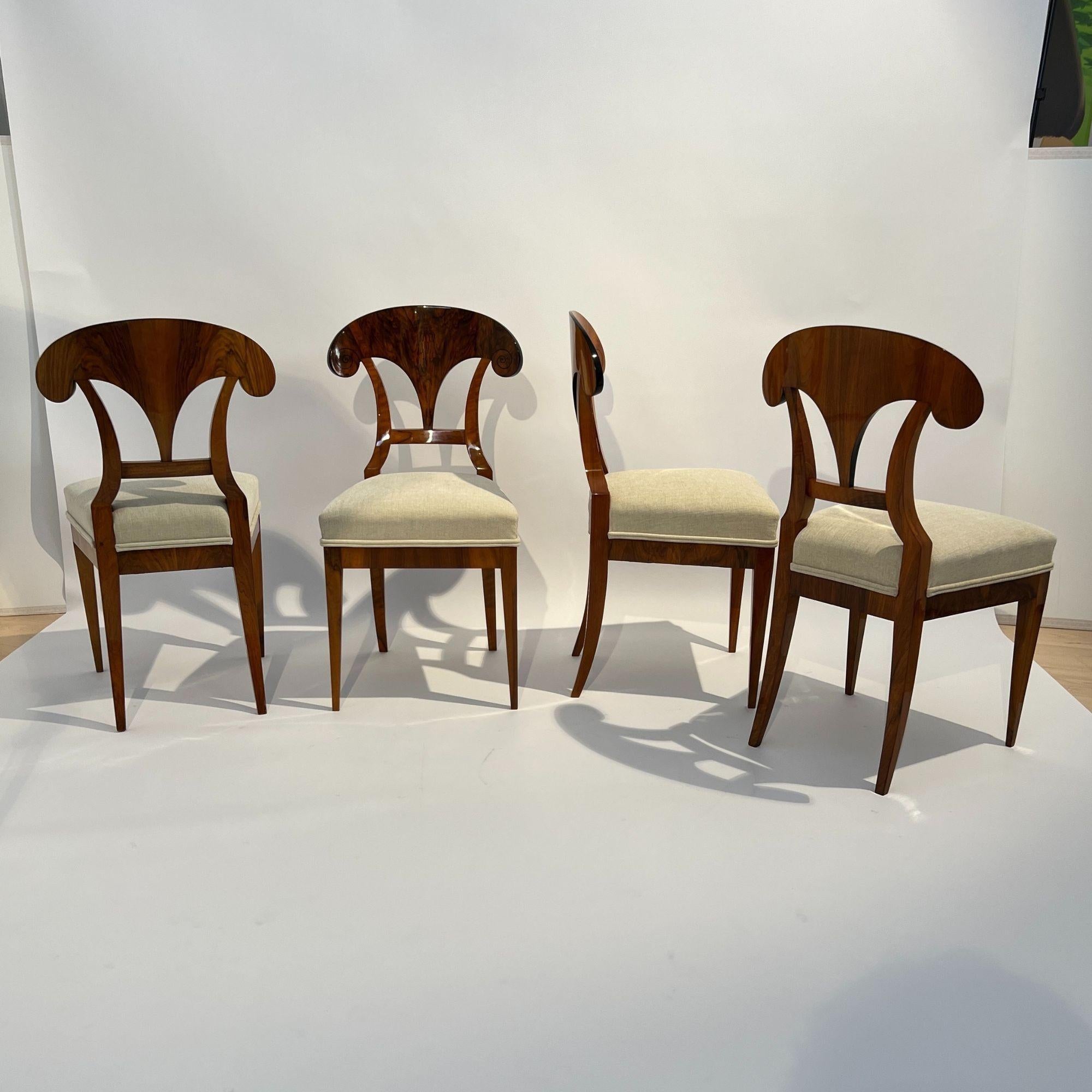 Classic, elegant set of four antique Biedermeier shovel chairs in walnut from Austria around 1830.
Walnut book-matched veneered and solid walnut. Original spirals painted with ink on the sides of the backboard.
Ebonized outside and inside edge of