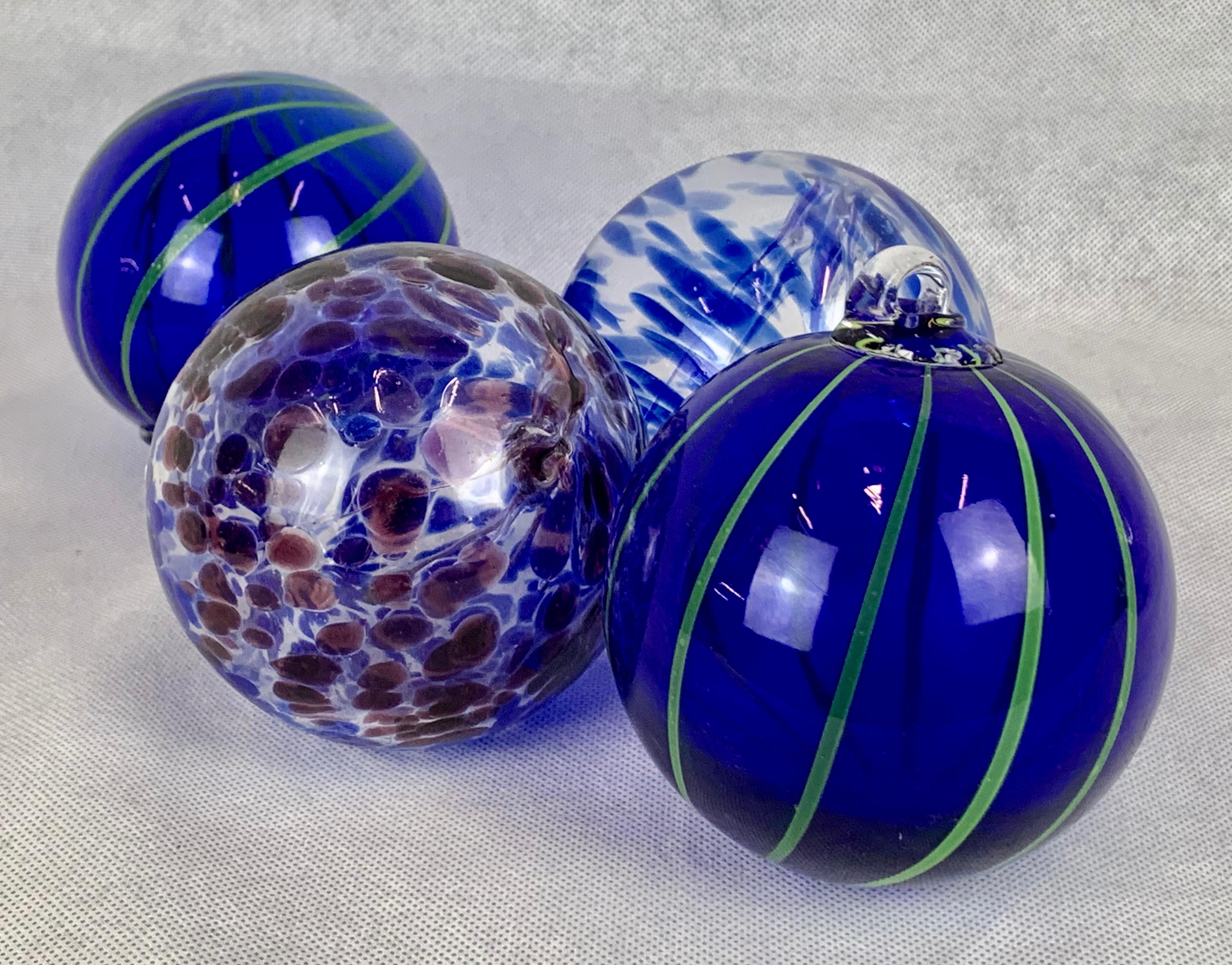 Set of four good size blown glass balls each with a glass loop for hanging. Of course they would also look great in a clear glass bowl.   If you are a cobalt blue lover these beauties are for you.
