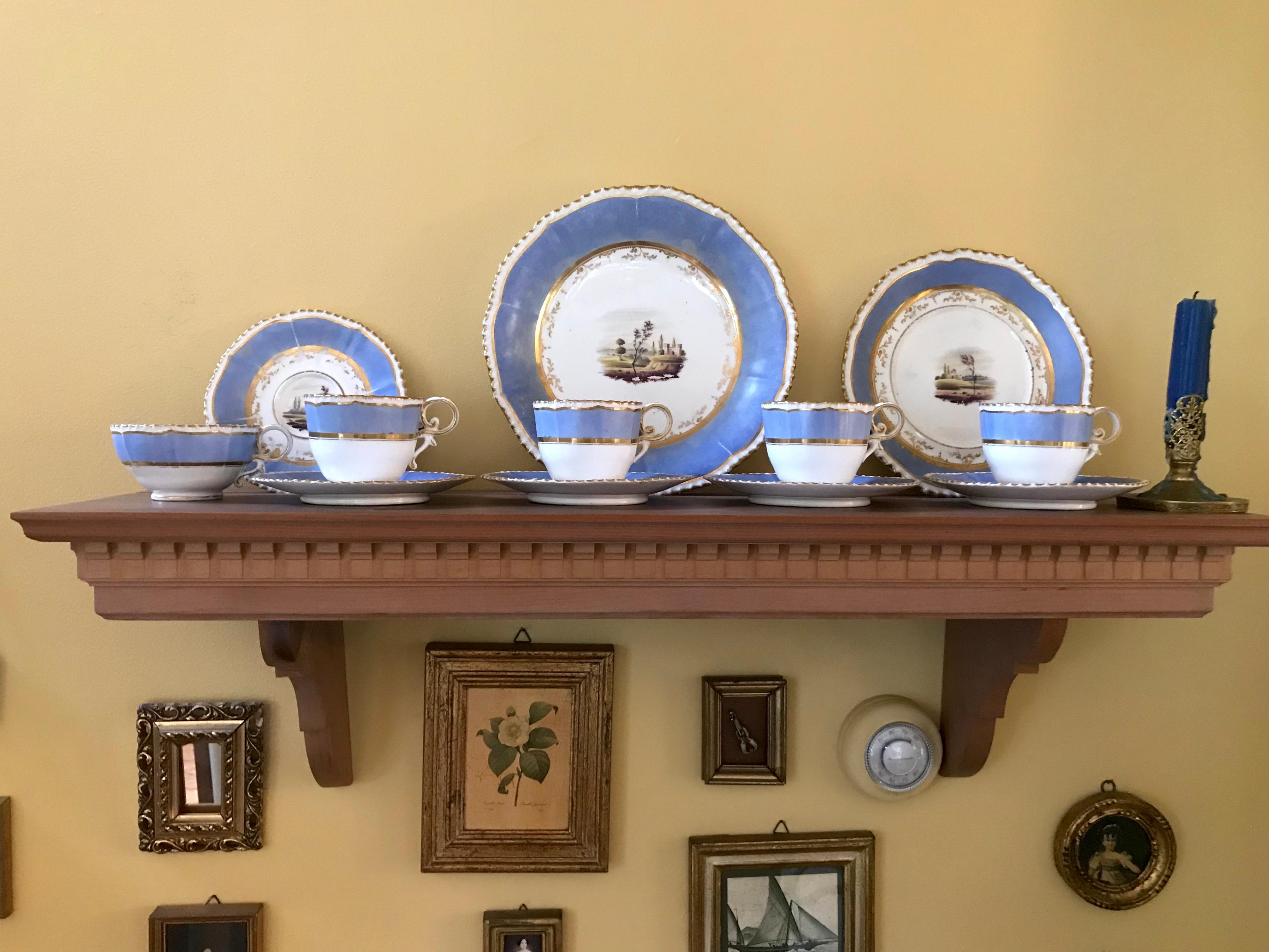Set of four blue and gilt painted English scenes coffee cups. Set of four pale blue and gilt painted coffee cups and saucers, biscuit bowl and plate, each with gilt shaped and scalloped rim, large blue band with further inset gilding centering on