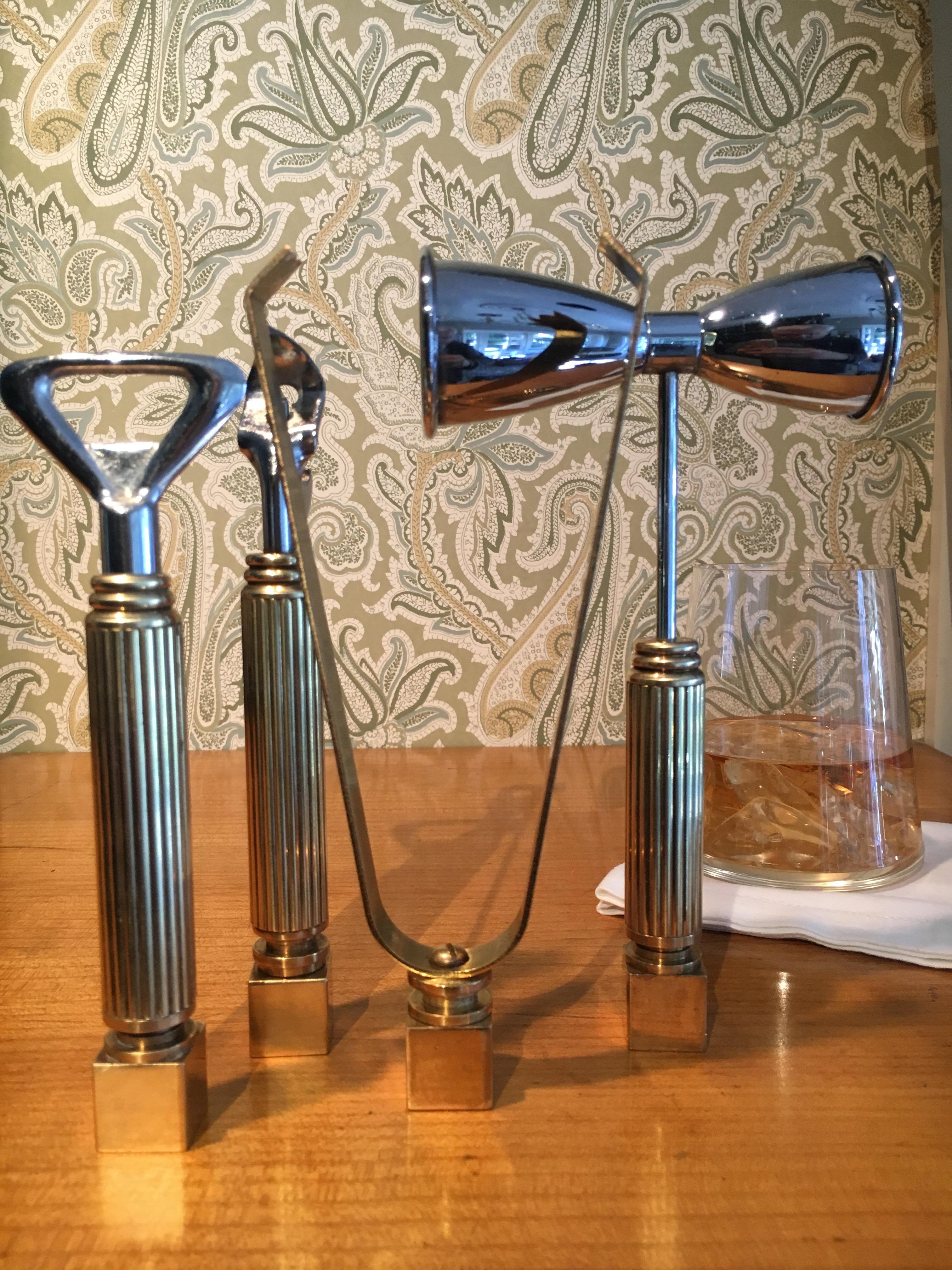 Set of four brass bar accessories, a substantial and heavy solid brass set. Can opener, bottle opener, double (two sizes) Jigger, ice tongs. Beautifully designed and weighted with brass block allowing all to stand in place!
 