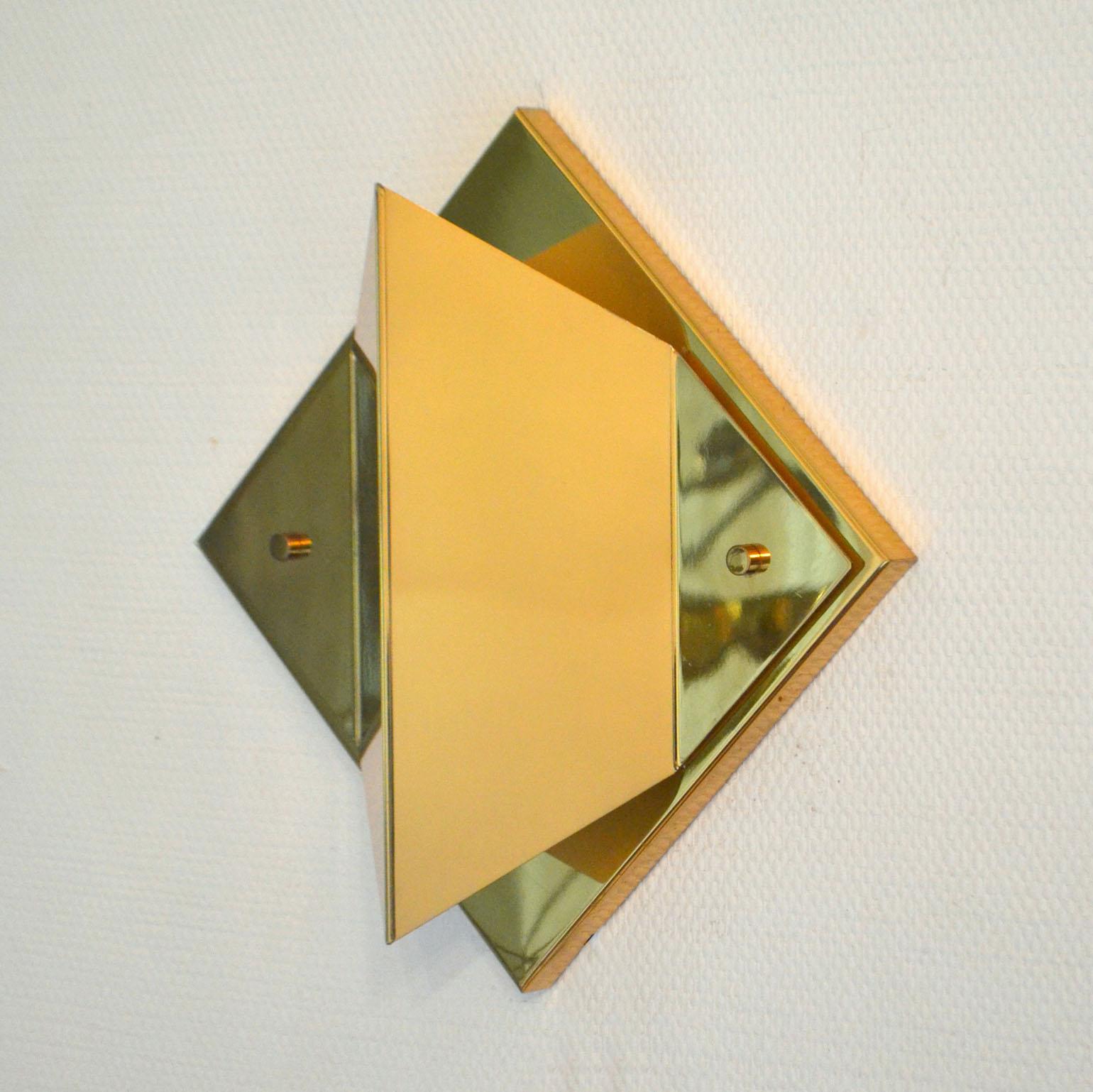 Four polished brass wall sconces are shaped like a diamond. 
A diamond is a quadrilateral, a 2-dimensional flat figure that has four closed sides. But the brass lamps would be categorized as rhombus; because it has four equal sides and its opposite
