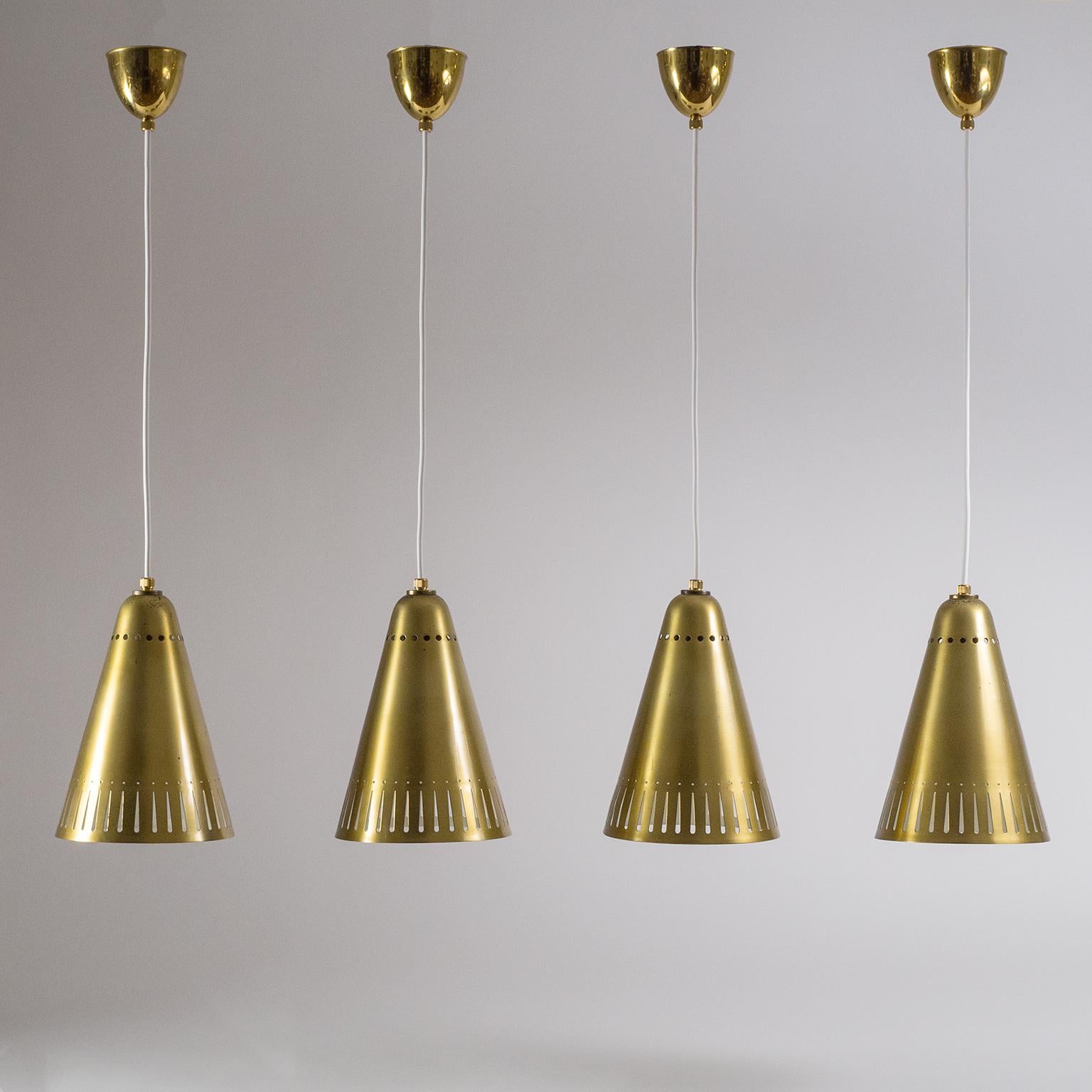 Lovely midcentury brass pendants from the 1950s. The all-brass cones have a very unique pattern of perforations which comes to life when lit. There is a charming patina of varying degrees on the brass and original white lacquer on the inside in very