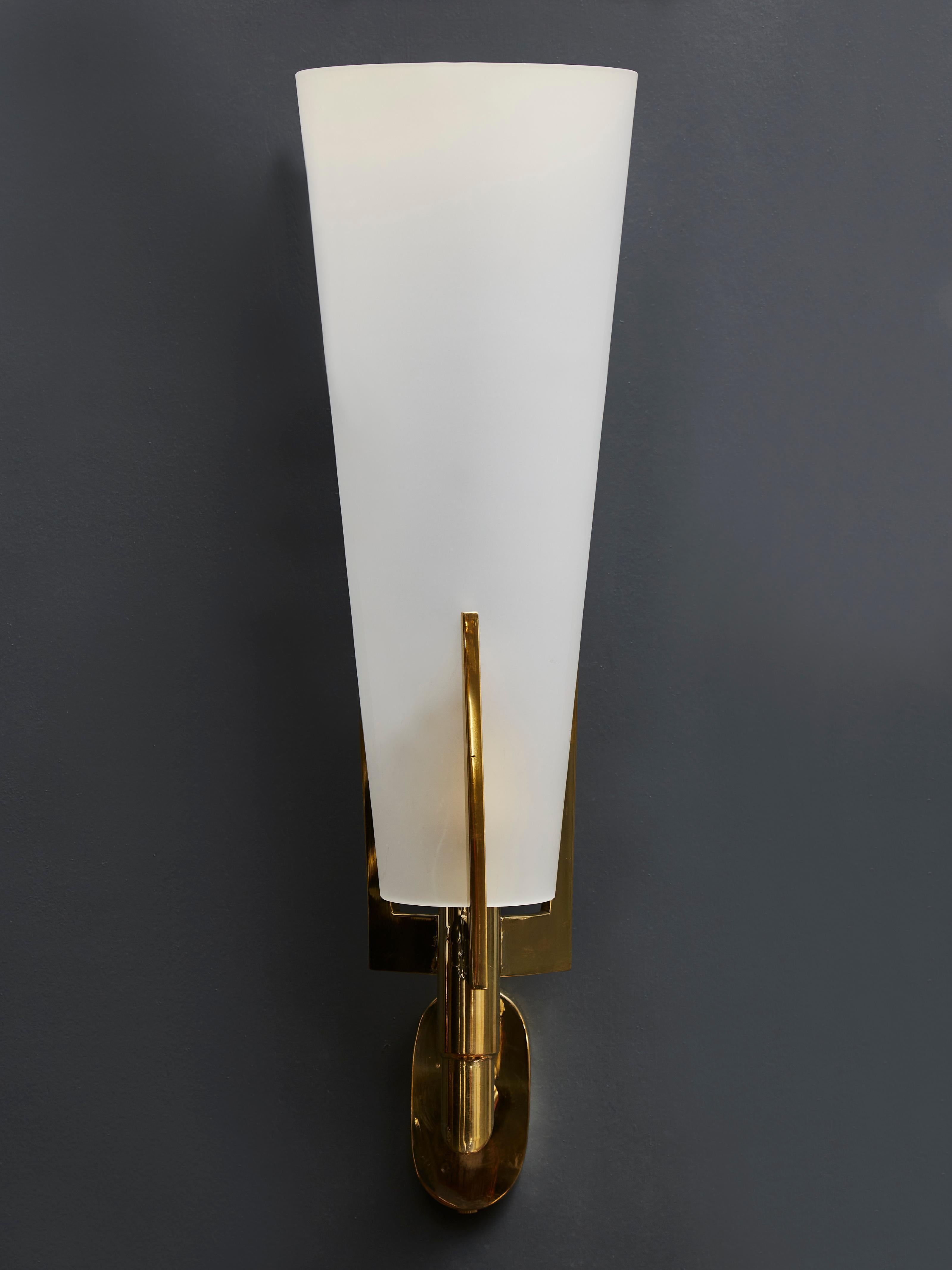 Set of four wall sconces made of a brass structure holding a tall white frosted glass cone.