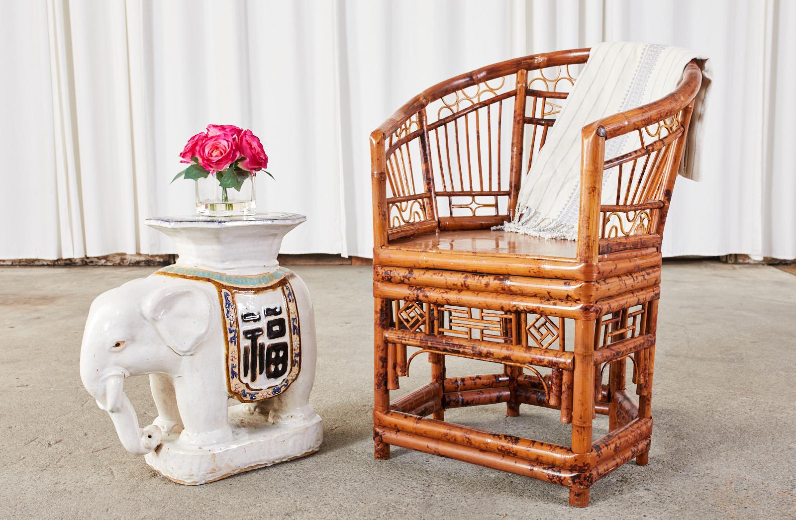 Captivating set of four English regency Brighton Pavilion style armchairs or lounge chairs crafted from bamboo and rattan. The chairs feature a horseshoe form bamboo frame decorated with open fretwork designs showcasing geometric patterns. The