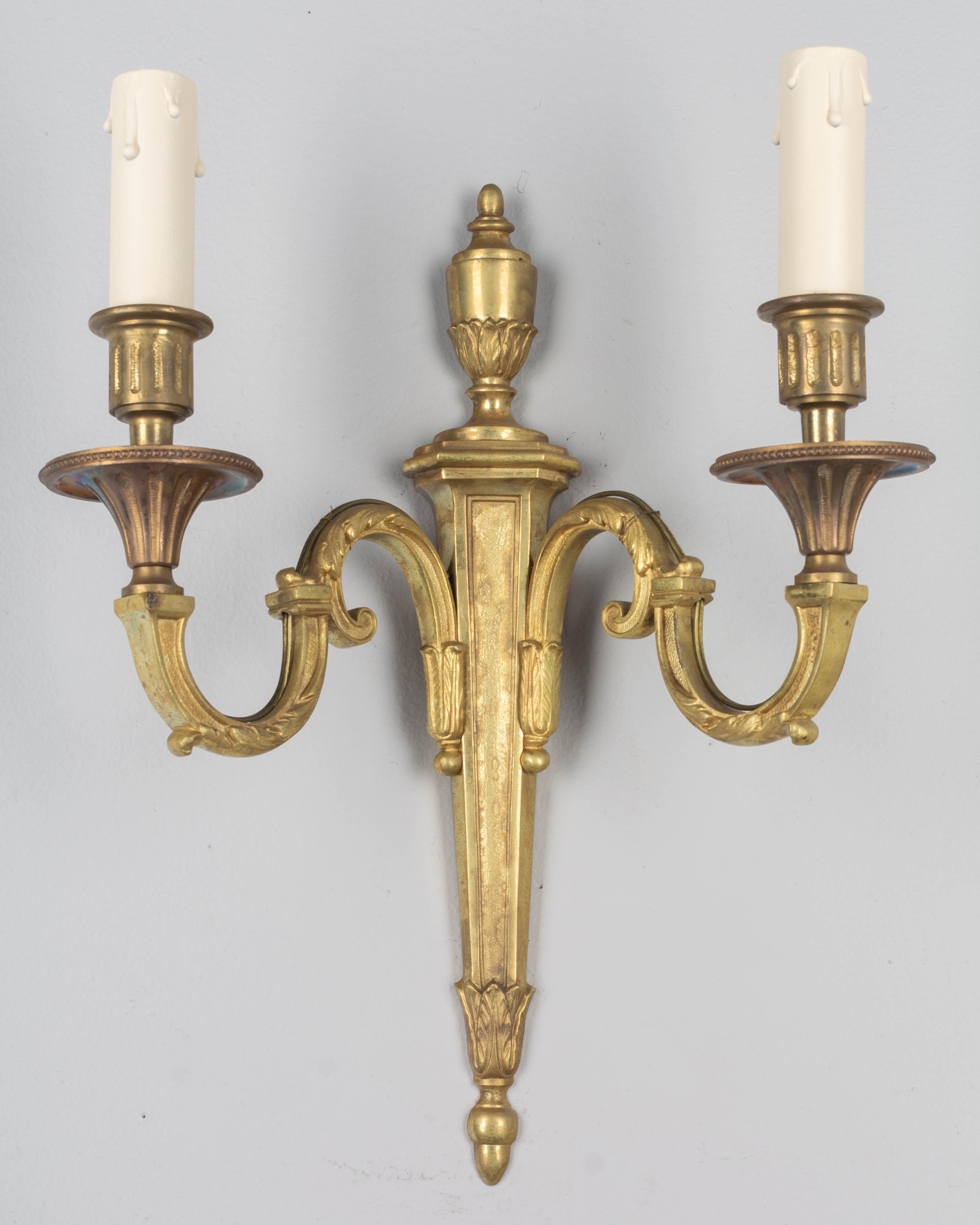 A set of four Louis XVI style French two-light bronze sconces with gold patina. Rewired with European sockets.