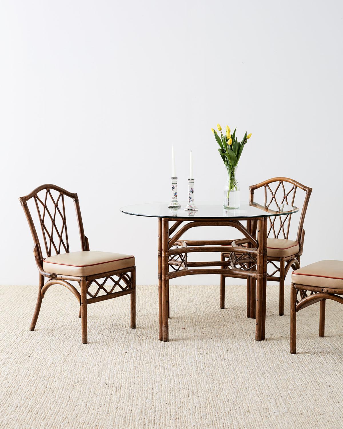 Stylish set of four bamboo rattan dining chairs by Brown Jordan. Featuring a bent rattan frame decorated with the Brown Jordan style lattice design on the splat and apron. The seat backs have a hump back crest and each seat is topped with a faux