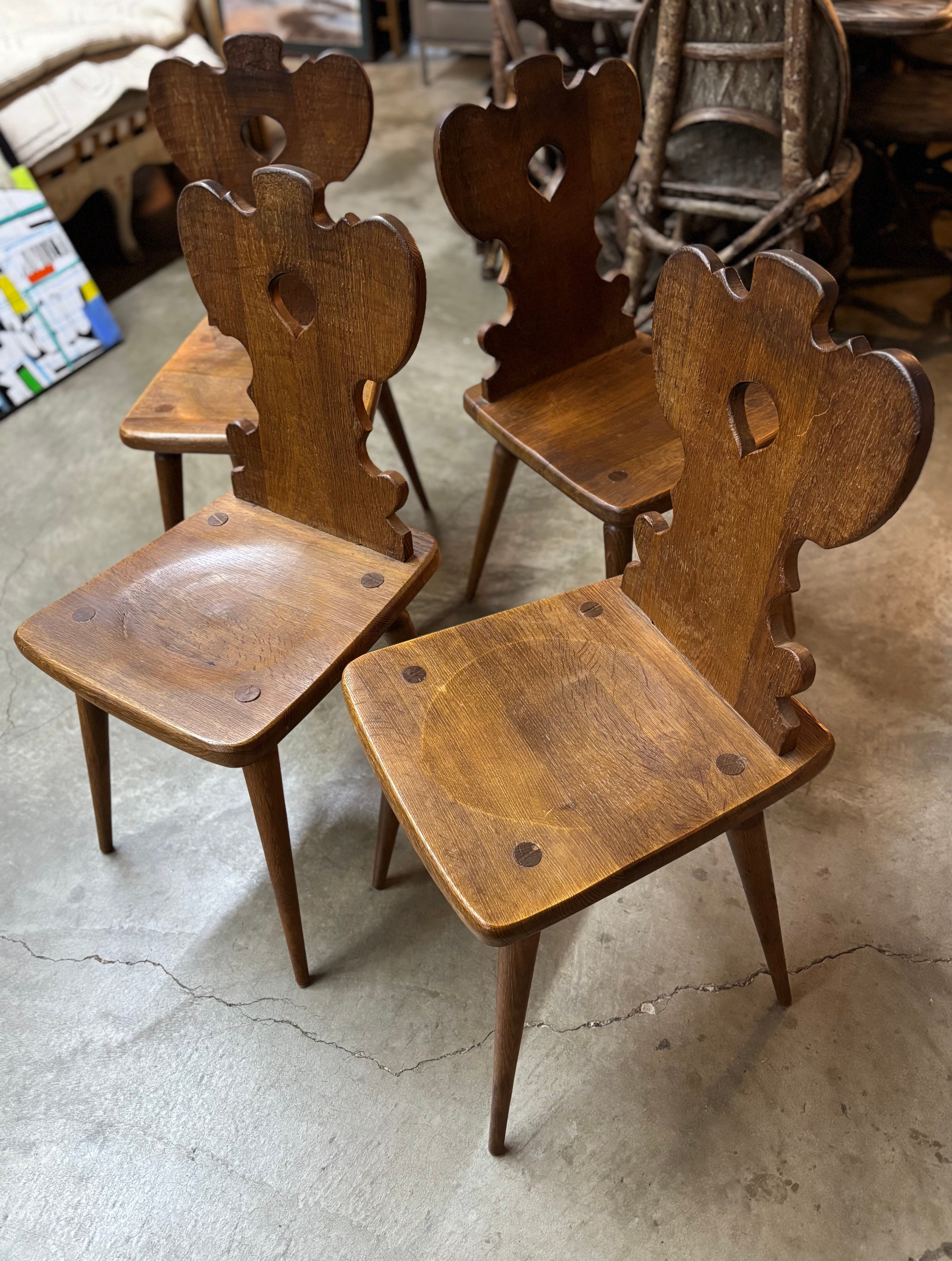 Ensemble de quatre (4) chaises de salle à manger brutalistes belges en chêne sculpté, vers les années 1940. Les chaises de salle à manger rustiques sont idéales pour un design rustique de type cottage country. Ces chaises de salle à manger en bois