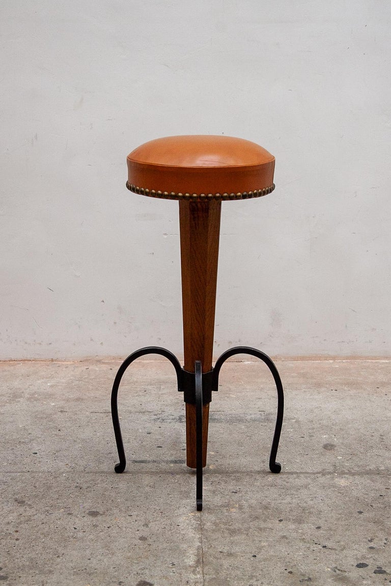 Set of four hand-crafted wrought iron bar stools with special hand stitched leather seats and bronze nails. The four bar stools are very special design of the Midcentury Modern look. All stools in perfect original condition.