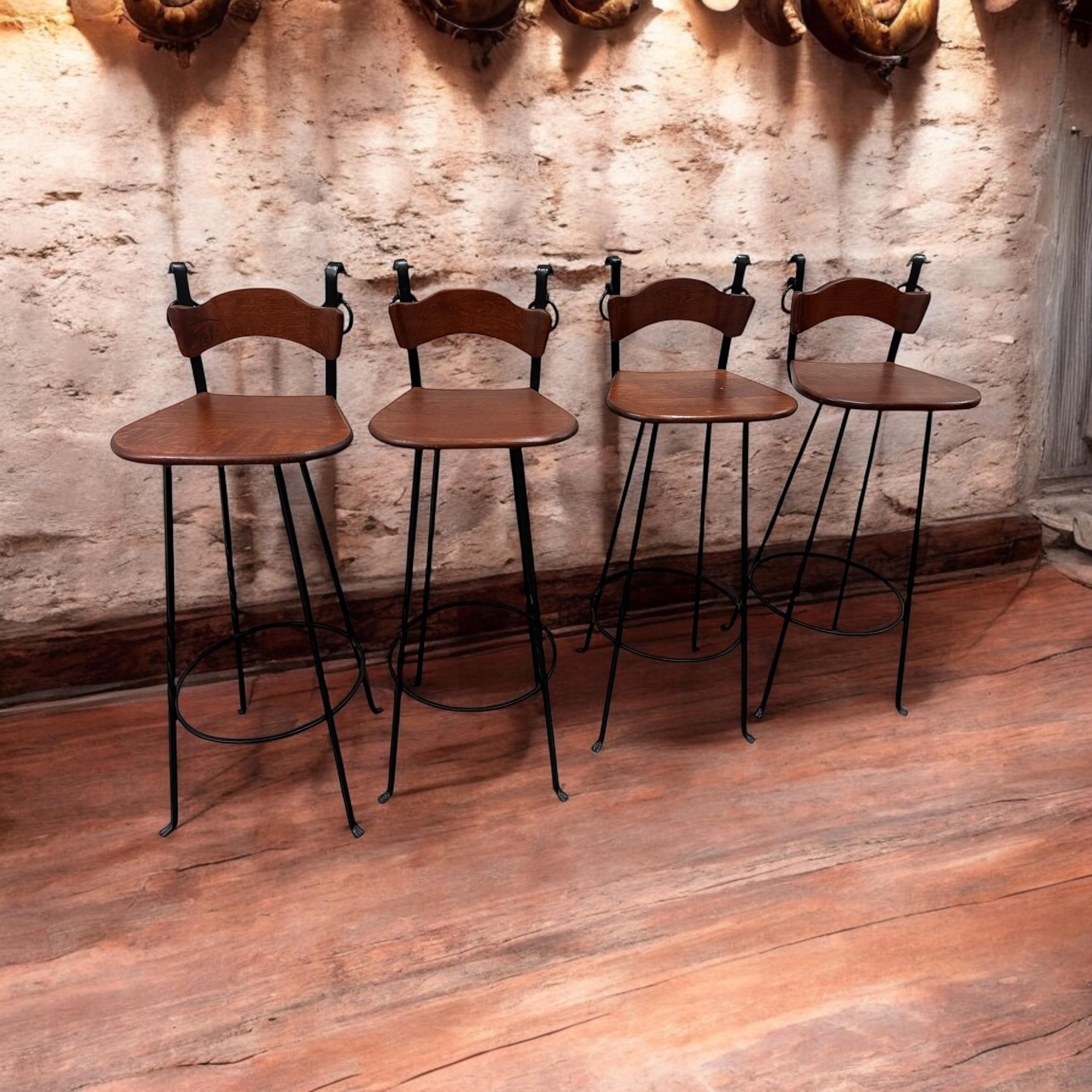 A gorgeous set of Brutalist barstools. Set of four 'Brutalist' bar stools, in wood and wrought iron, Germany, 1970s. A curved seat with iron frame and handles. The curved form makes sure the stool has a stabile seat, emphasized by the metal ring as