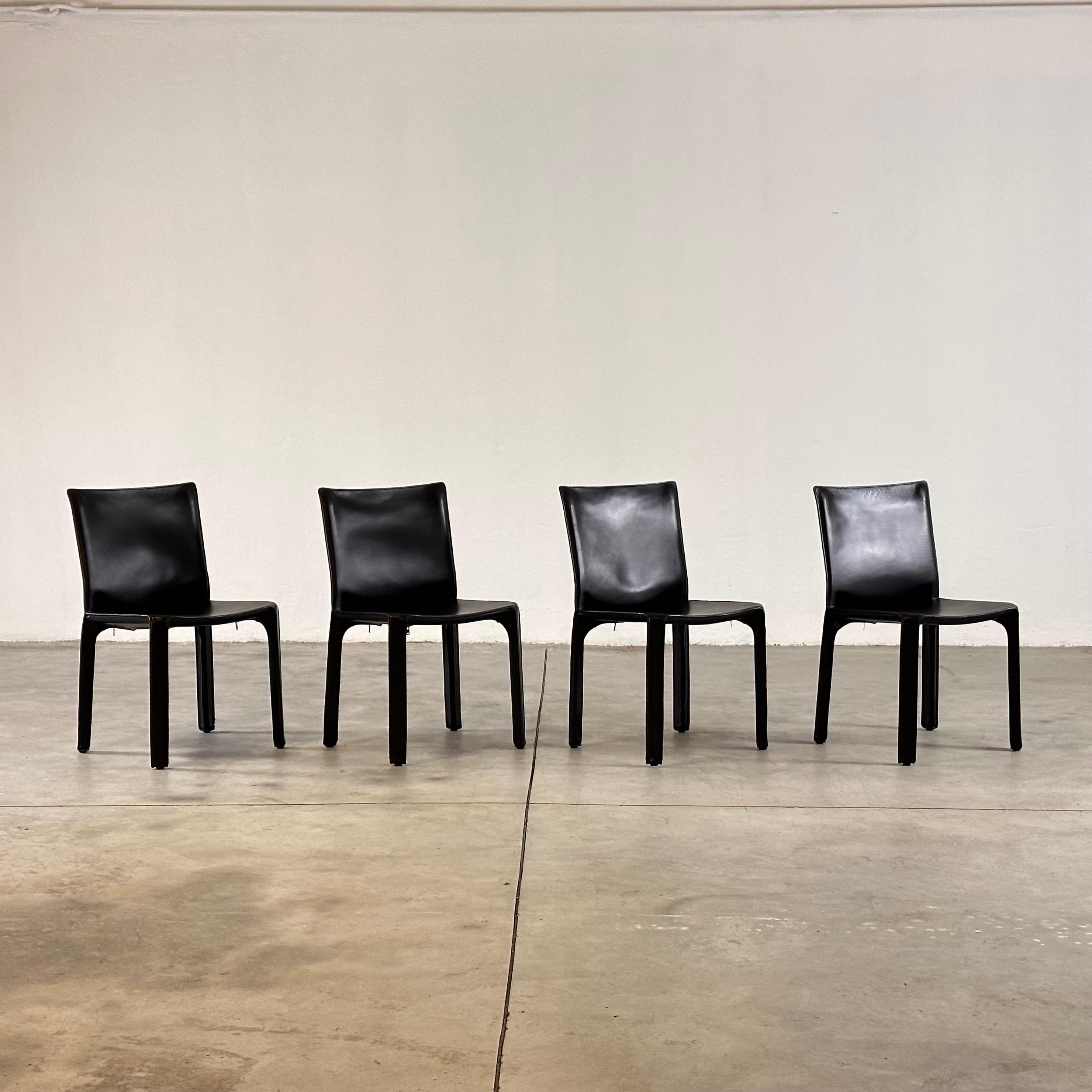 A set of four Italian design icons in black saddle leather.

When first produced in 1977, the CAB was the first chair to feature a free-standing leather structure, inspired by how human skin fits over our skeleton. The leather upholstery is