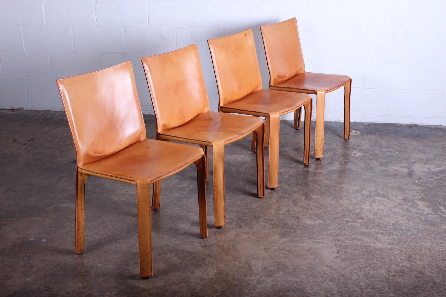A set of four patinated leather cab chairs designed by Mario Bellini for Cassina.