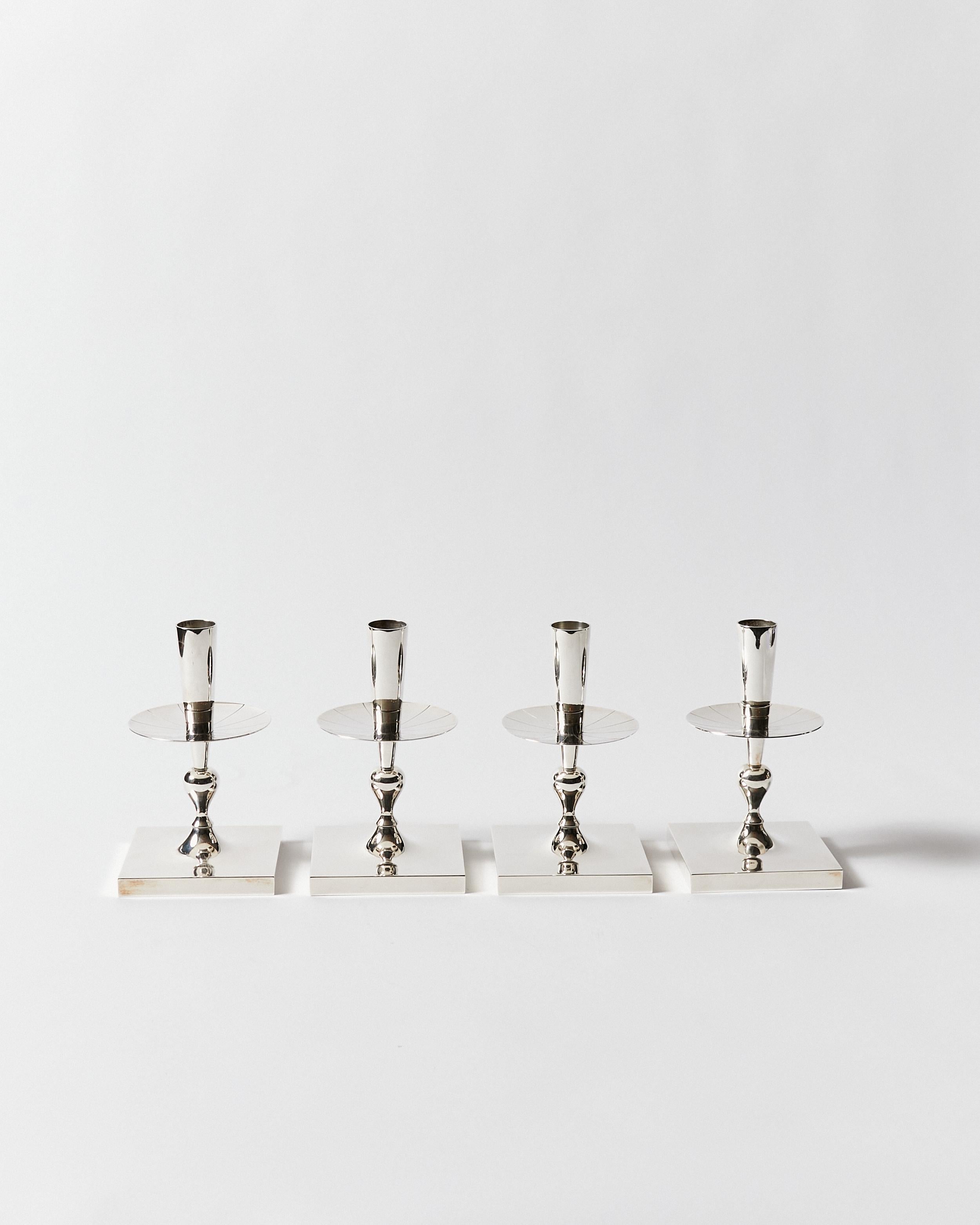 Set of four candlesticks with a square base, stylized column and engraved drip plate. Designed by Tommi Parzinger for Dorlyn-Silversmiths. Signature stamp on bottom.