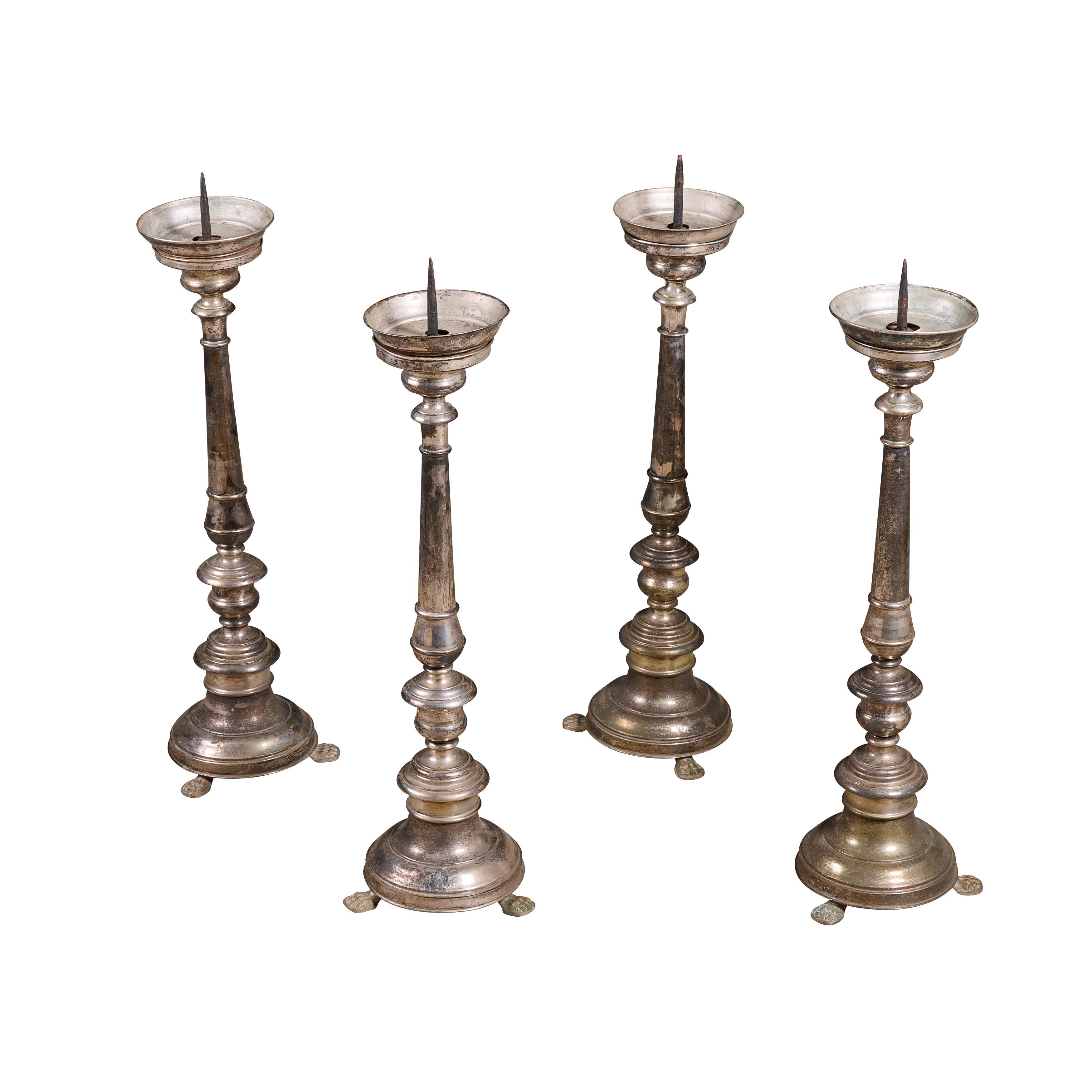 Set of four metal plated candle sticks with feet and great patina.


