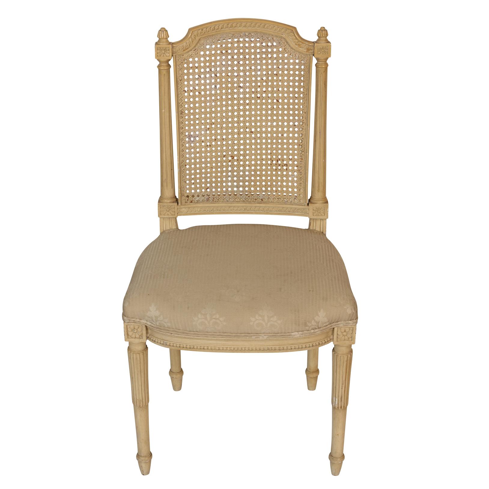 A set of four dining chairs with caned backs, rosette details and carved legs with upholstered seats.  Damage to some caning and stains to some uphosltery. One chair will need recanning on the back.