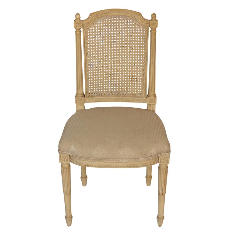 A set of four dining chairs with caned backs, rosette details and carved legs with upholstered seats.