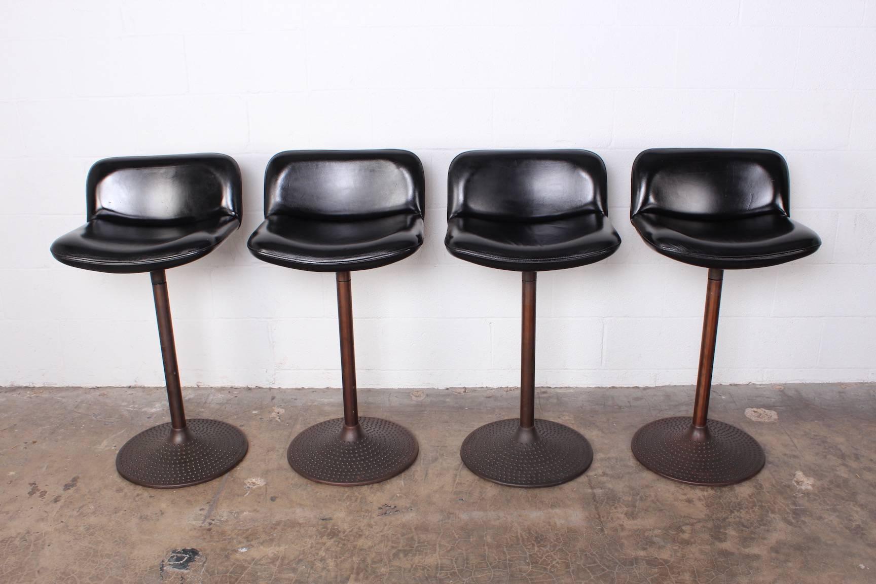 A set of four bronze stools with original leather upholstery. Designed by Ilmari Tapiovaara.