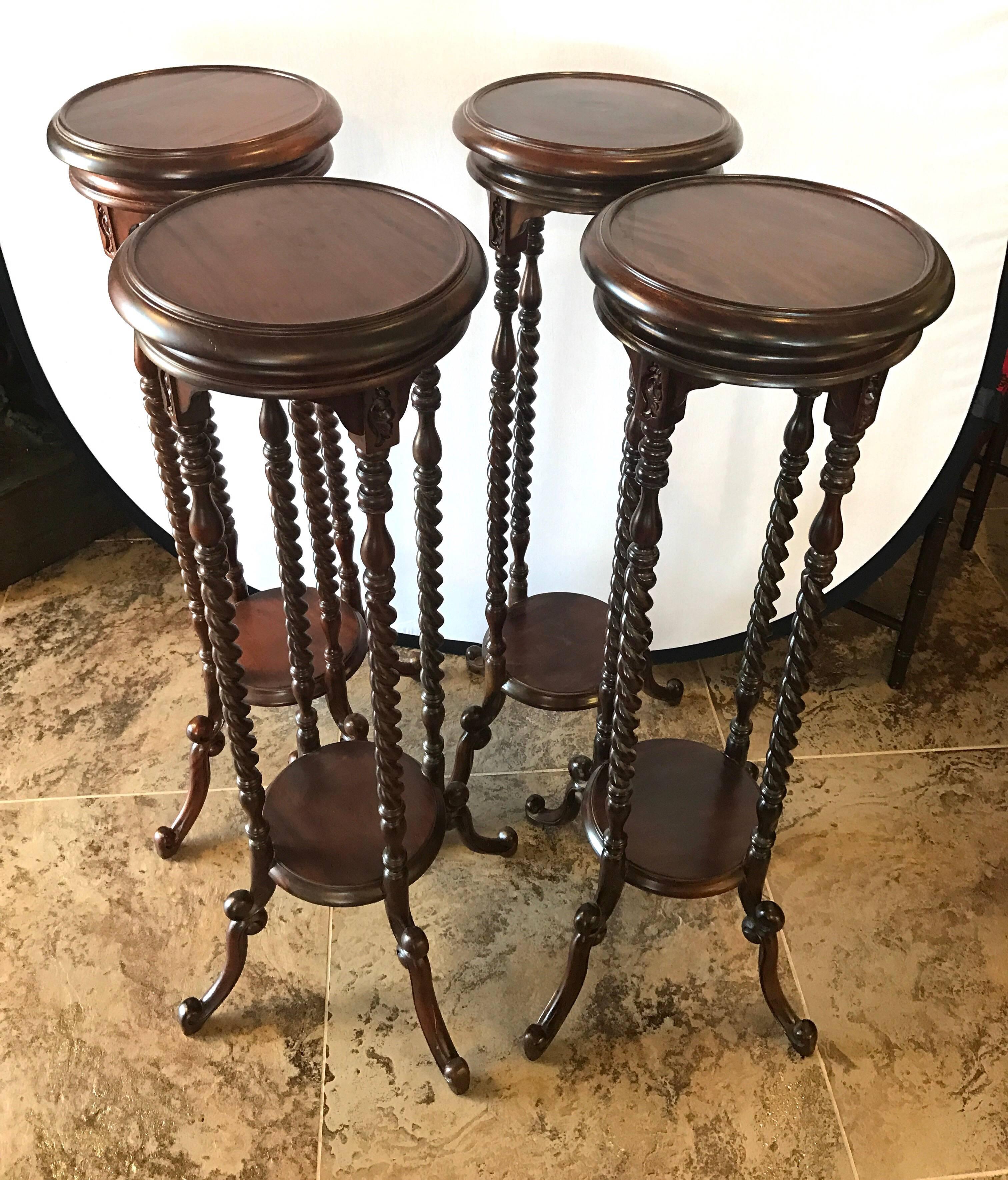 Set of four mahogany pedestals stands with intricate carvings and turned legs.