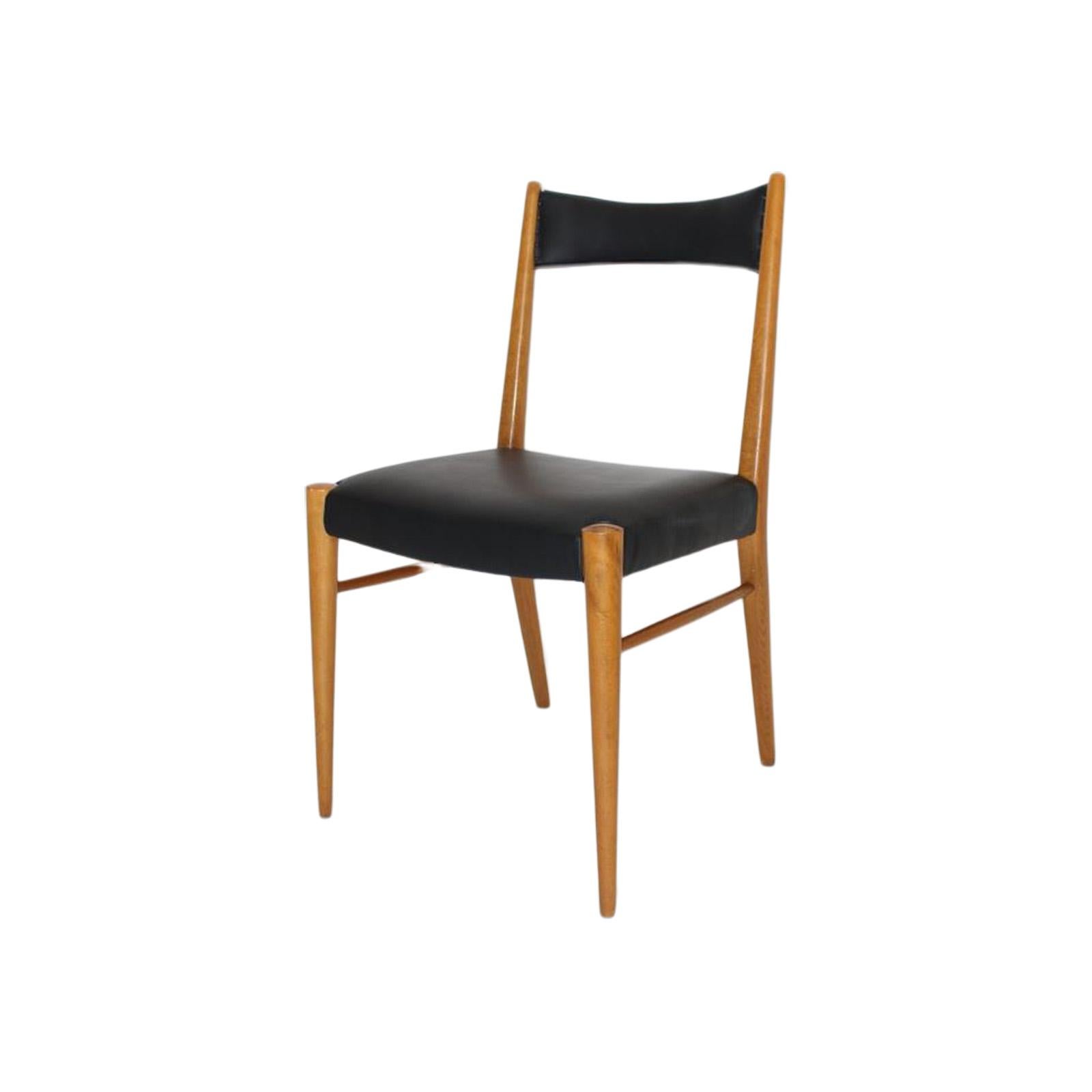 His set of four dining room chairs were designed by the Viennese architect Anna-Lülja Praun in 1953 and manufactured by Wiesner-Hager. The chair frame is made of beech and the upholstered seat and back are covered with black faux leather and