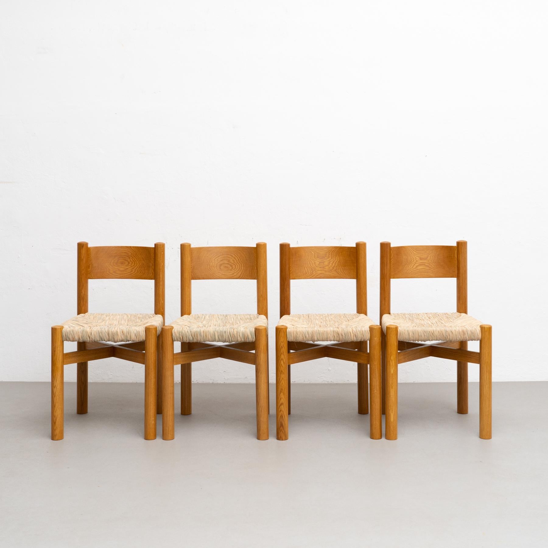 Set of Four Chairs After Charlotte Perriand, 
by unknown manufacturer, circa 1980 in France.

Materials:
Wood and rattan.

In original condition, with minor wear consistent with age and use, preserving a beautiful patina.


