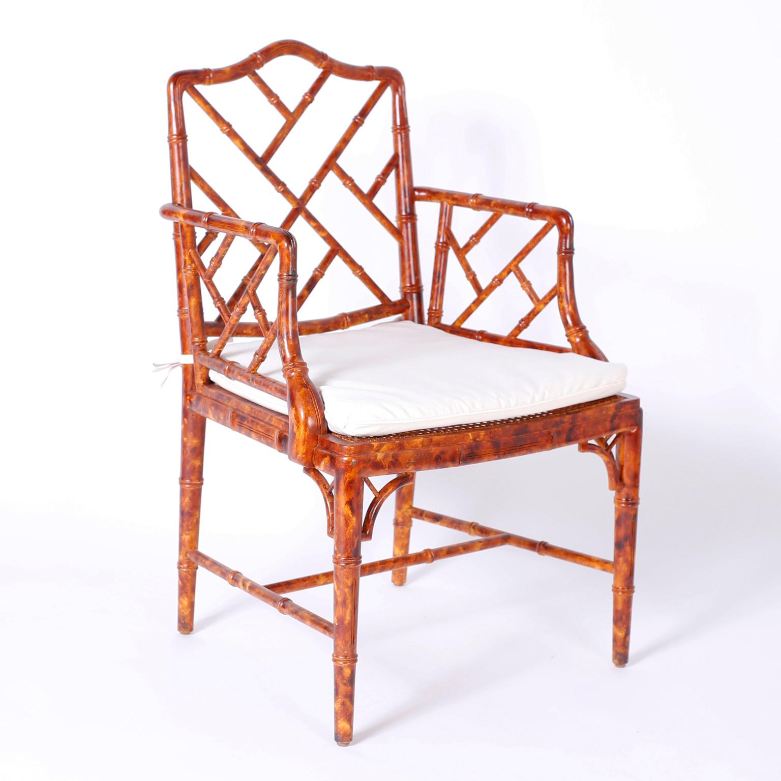 Set of four vintage carved wood dining chairs with a Classic faux bamboo Chinese Chippendale form, dramatic faux tortoise finish, and tie back cushions over caned seats.