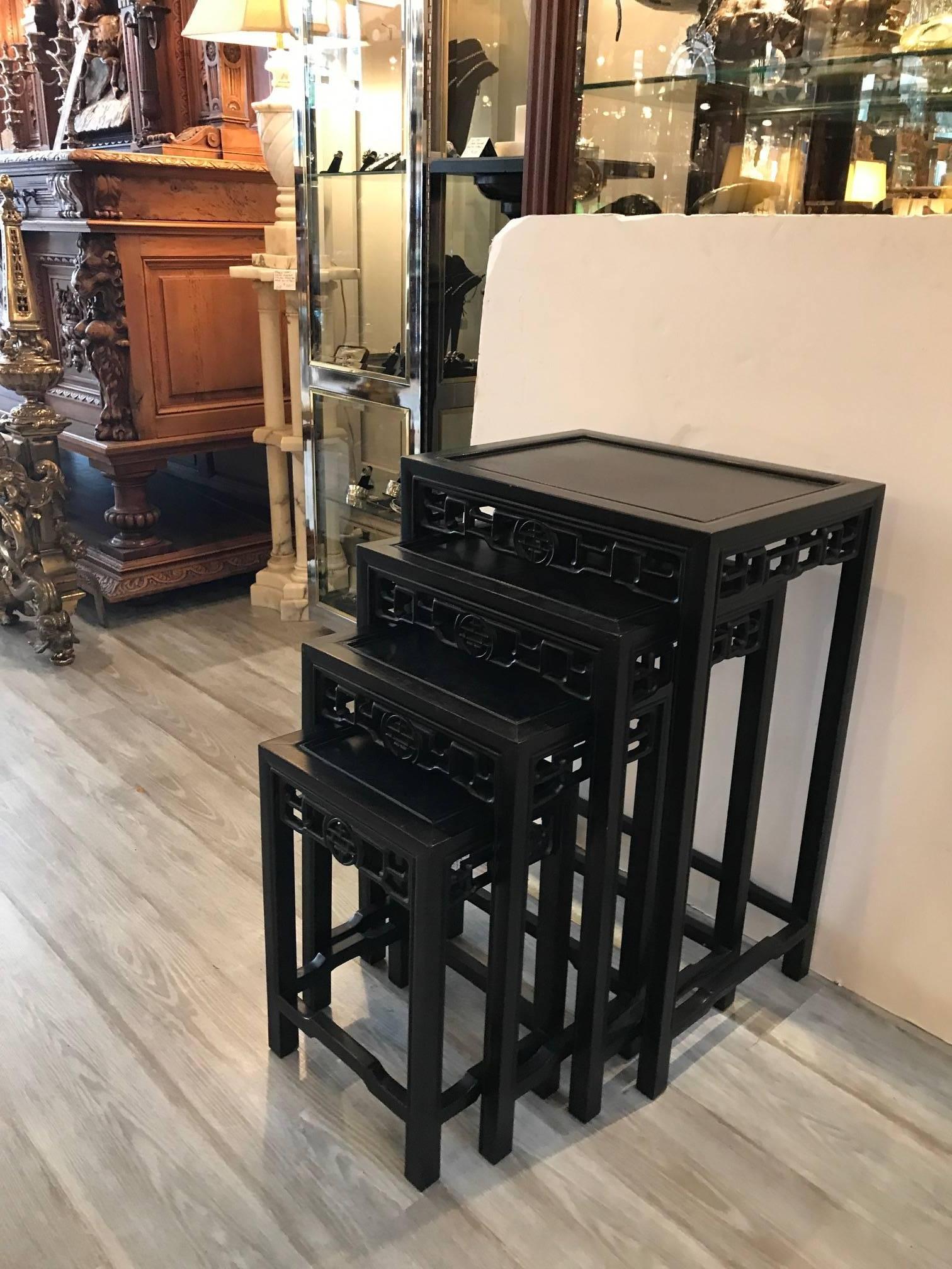 A set of four ebonized wood Chinese nesting tables. The tables fit neatly into one another for a small space but can be displayed staggered. The aprons are nicely carved and repeated on the set.