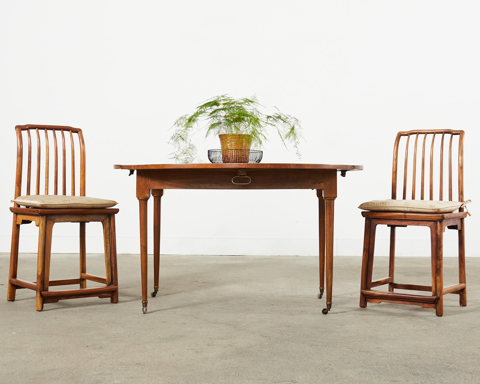 Gorgeous set of four Chinese country provincial qing style dining chairs crafted from hardwood probably elm. The frames have a square shaped spindle back that scrolls or arches at the top crest. The seat features a raffia or grasscloth lacquered