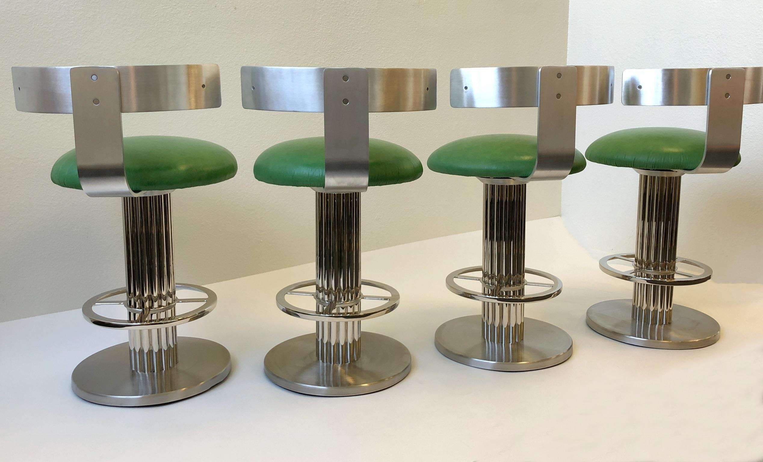 A glamorous set of four aluminium and stainless steel barstools design in the 1980s by Design for Leisure Ltd. The barstool have been newly restored and recovered in a soft distress apple green leather. The stools swivel 360. 

Dimensions: 33”