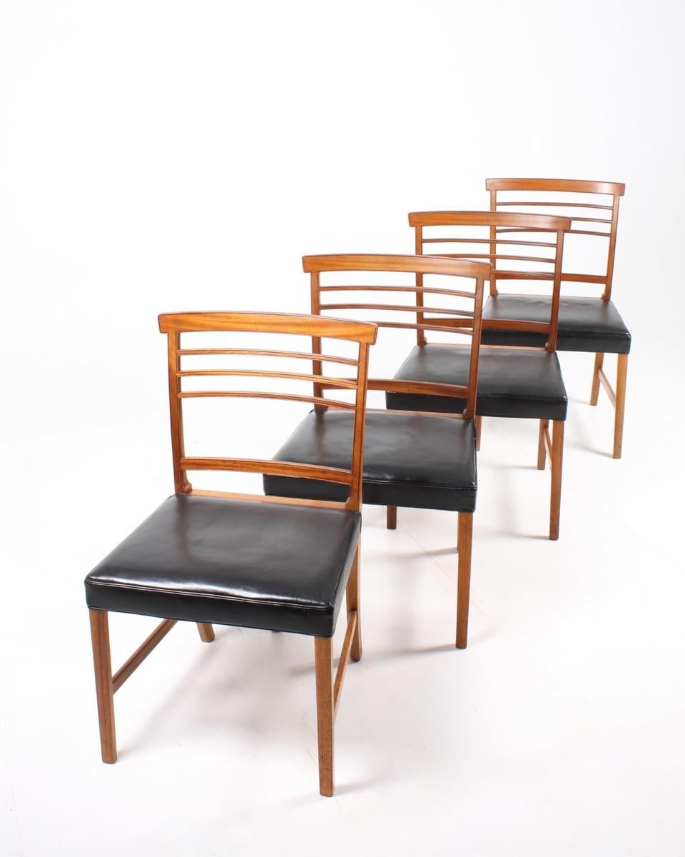 Set of four side chairs in mahogany with seats in black patinated leather. Designed by Ole Wanscher for A.J. Iversen cabinetmakers Denmark in the 1950s. Great original condition.