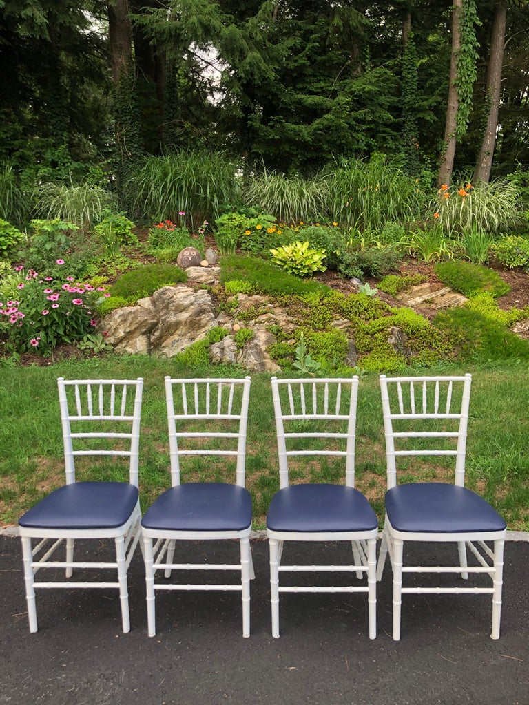 Set of four classic white wooden Chiavari chairs with padded navy seats. Nice faux bamboo design. Perfect to go around that white kitchen table or office table. Removeable padded navy blue seat cushions covered in a durable faux leather/high grade