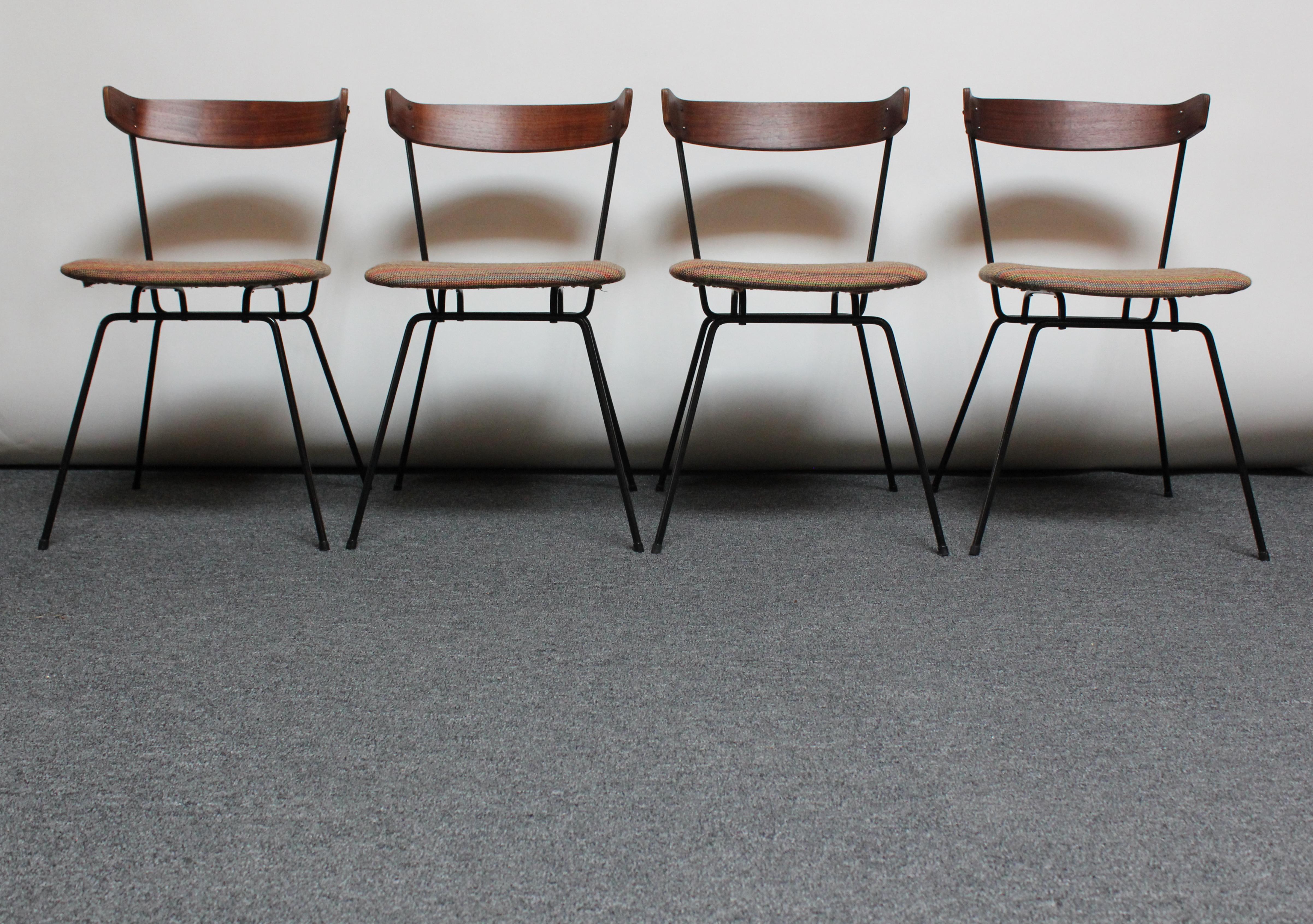 Set of four minimal, yet elegant dining chairs designed in 1951 by Clifford Pascoe for Modernmasters. The sculptural walnut backrests of the chairs are attached to the iron uprights through bolts (two on each side). The seats have been reupholstered