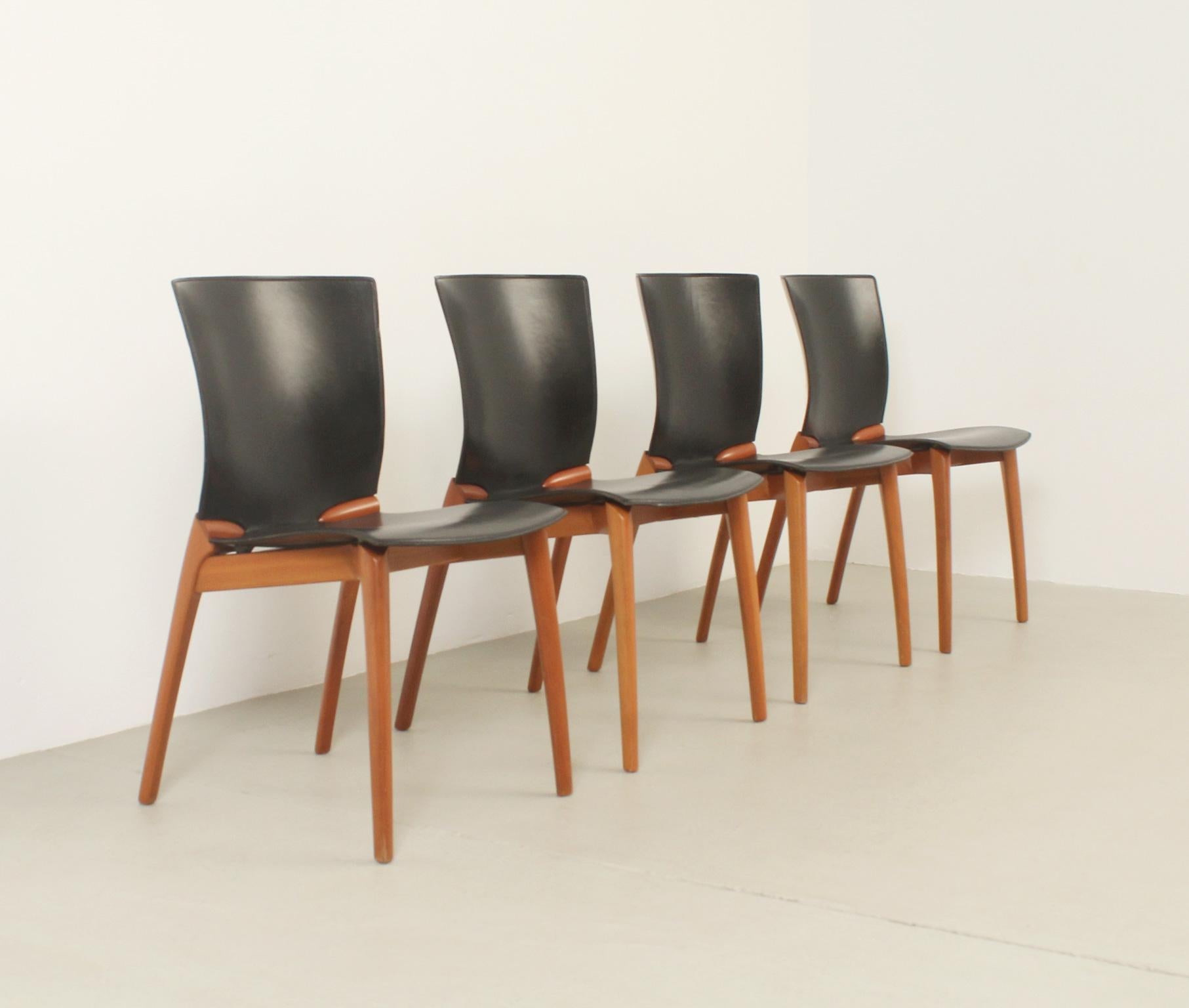 Ensemble de quatre chaises Cos conçues en 1994 par le designer espagnol Josep Lluscà pour Cassina, Italie. Structure en bois de cerisier et cuir noir. Signé avec le label Cassina.