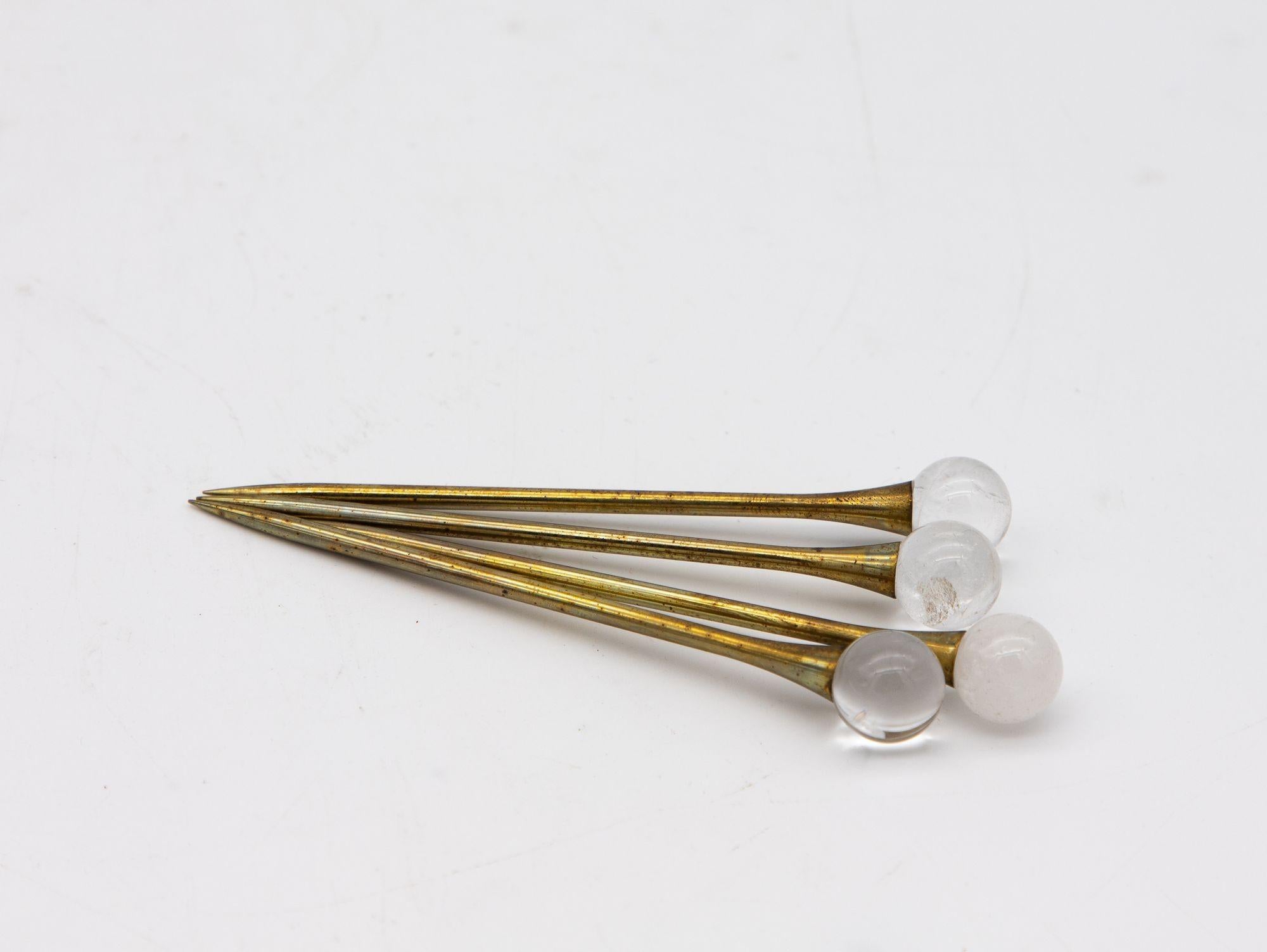 A set of four crystal and gold cocktail stirrers or picks is a collection of elegant barware accessories. The stirrers are made of sparkling crystal with a gleaming gold finish and are designed to be used as swizzles in cocktails to mix and blend