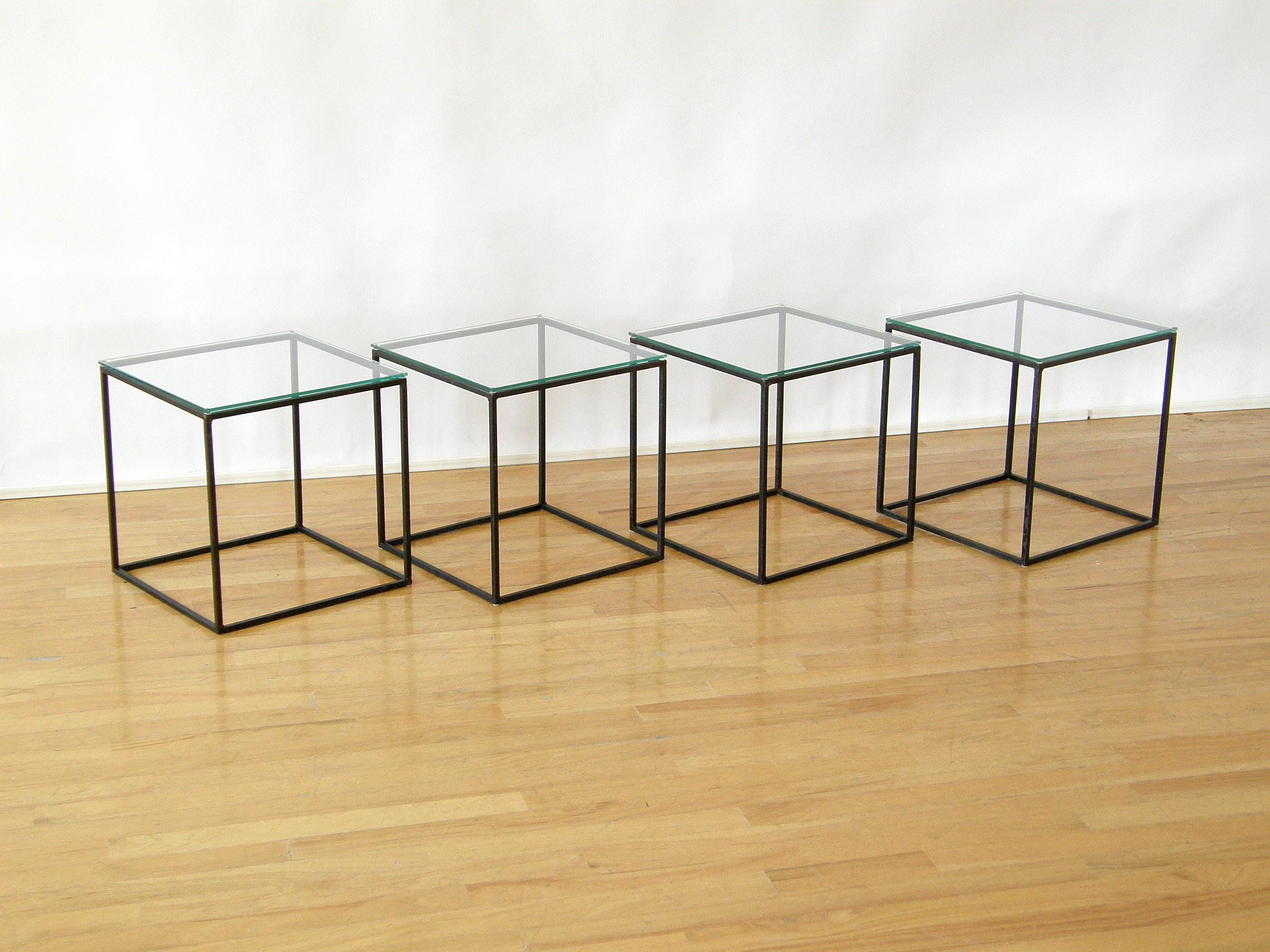 This circa 1950s or 1960s set of four cube tables have open frame iron bases and glass tops. They can be used together as a coffee or cocktail table, separately as side tables or chair side drink stands, or as platforms for display or plants. The