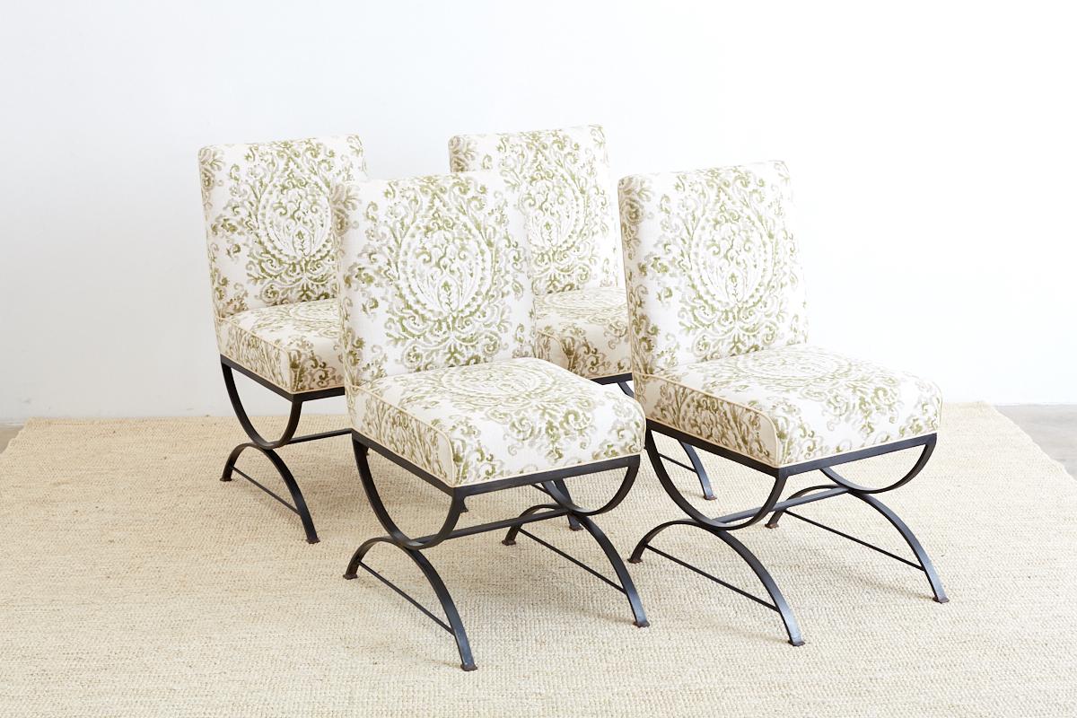 Stylish set of four wrought iron dining chairs featuring an x form curule style base. Heavy and solid made from bars of iron with round stretchers and square feet. Topped with a thick upholstered seat of organic linen fabric with a botanical style