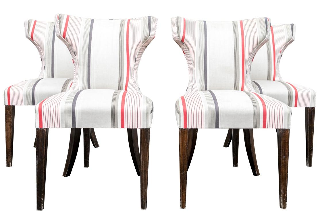 Set of four custom upholstered dining chairs with slightly curved and tapered backrest that are reminiscent of the iconic Klismos style. The chairs  with a cinched backrest with a comfortable curve and resting on tapering front and splayed back