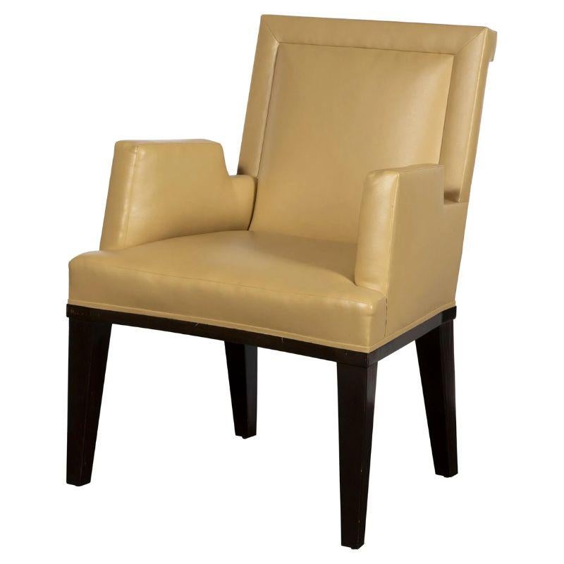A set of four custom Jonas faux leather arm chairs. The set of four chairs are upholstered in a neutral color tan faux leather and sit on dark wood legs. The chairs are a contemporary style with square backs, straight arms and legs and modern angles
