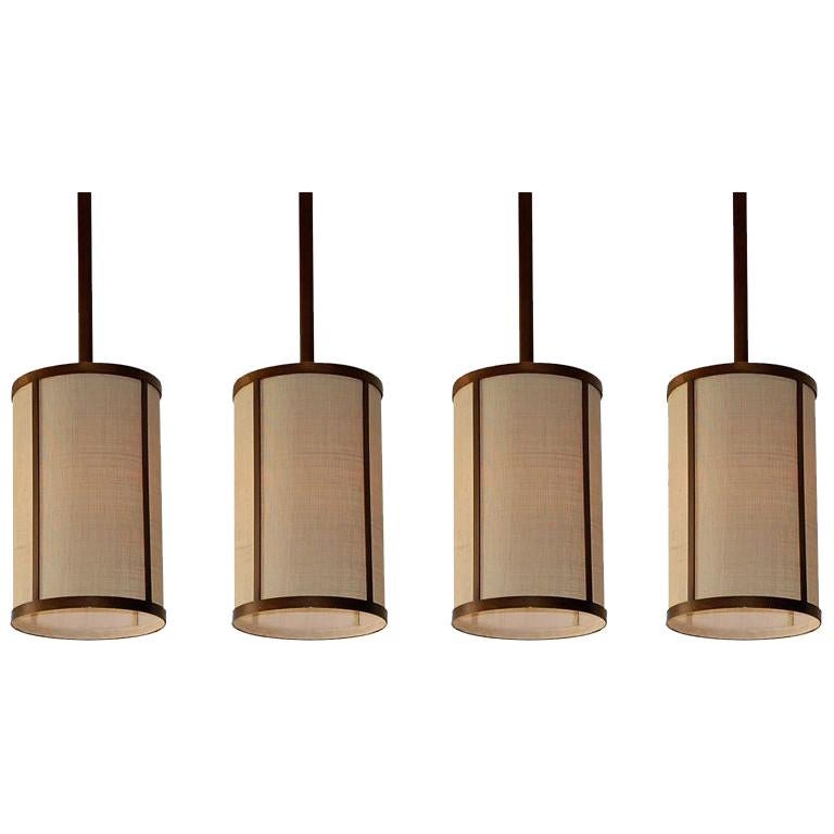 Set of Four 'Cylindre' Patinated Brass and Raffia Pendant Lights, Design Frères