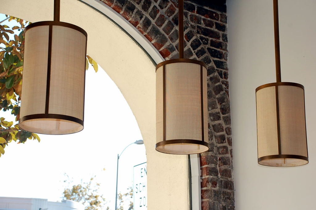 Organique Ensemble de quatre lampes à suspension 'Cylindre' en laiton patiné et raphia, Design Frres en vente
