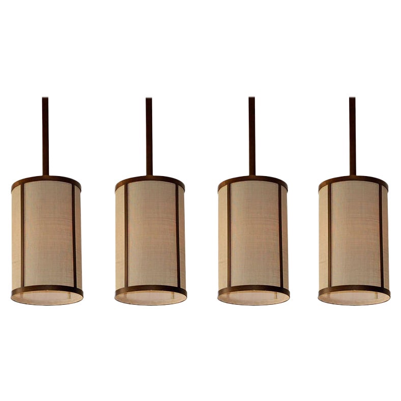Ensemble de quatre lampes à suspension 'Cylindre' en laiton patiné et raphia par Design Frres en vente