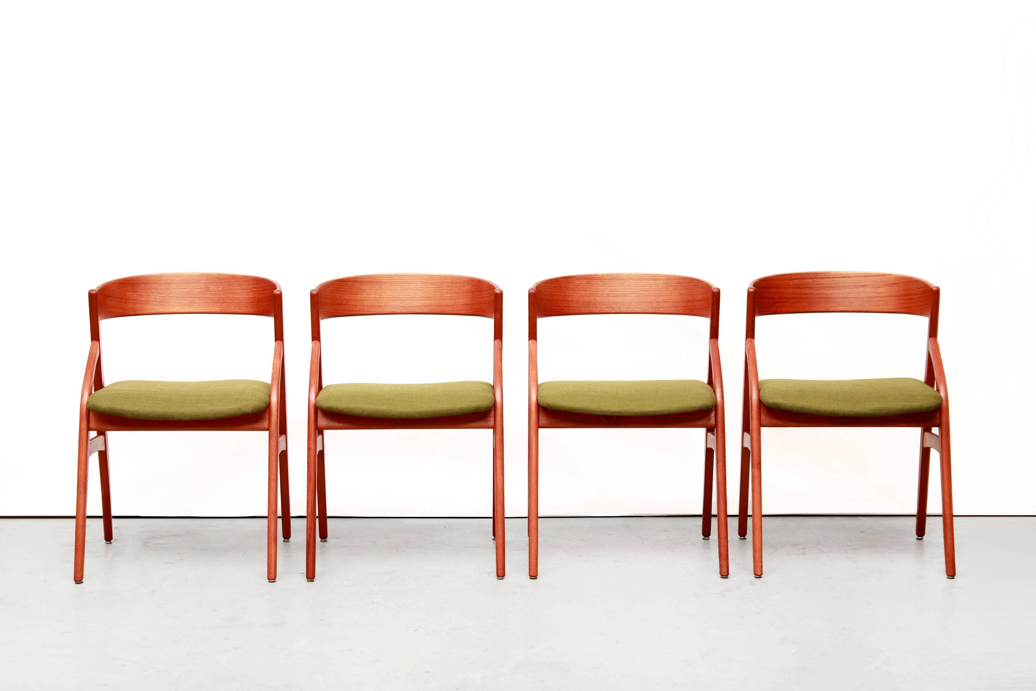 Beautiful set of four teak dining room chairs designed by the Danish designer Kai Kristiansen. These organically designed chairs are made of teak veneered plywood back and solid teak frame with green upholstered seats. These chairs are of high