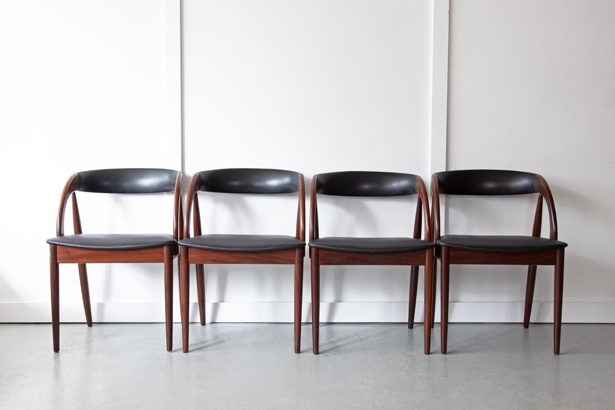A set of four Danish dining chairs, produced by Orle Møbelfabrik, with beautifully curved backrests and arms. The frames are made from solid teak and the seats and backrests have been newly upholstered in black faux leather. 
