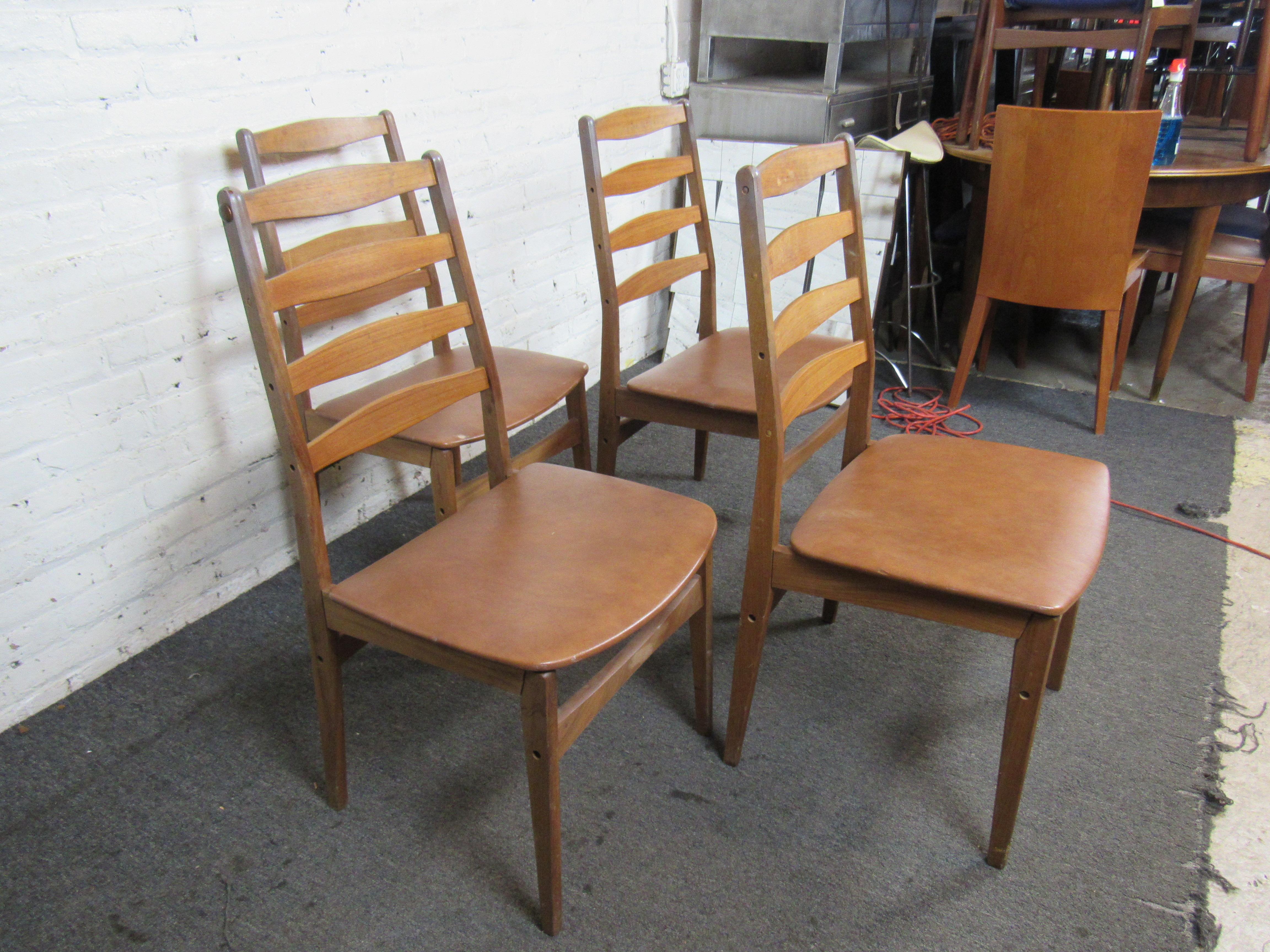 Pairing sculpted teak frames with upholstered vinyl seats, this set of four Danish dining chairs is a great way to add timeless and versatile Mid-Century Modern style to a dining room. Please confirm item location with seller (NY/NJ).