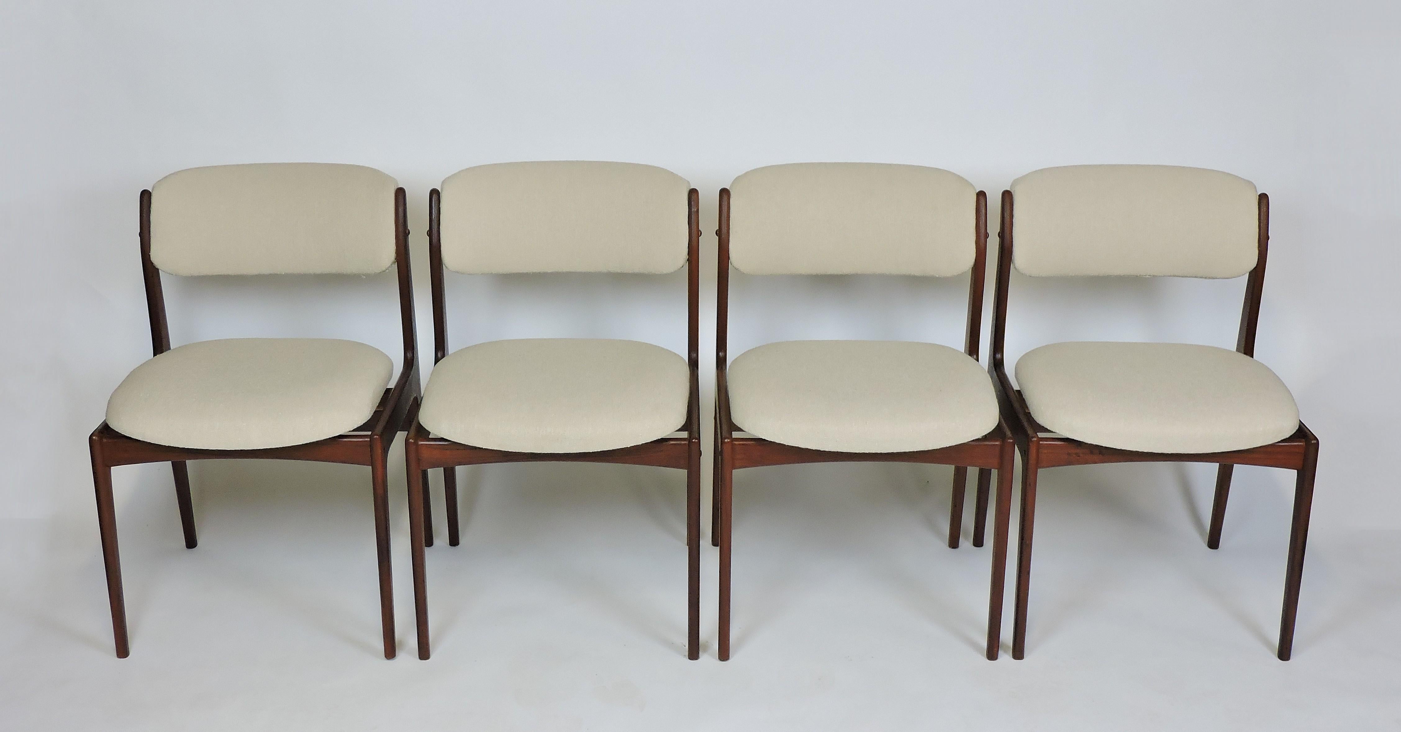 Beautiful set of four teak dining chairs in the style of Erik Buck. These chairs are made of solid teak with curved upholstered backs, floating seats and tapered legs. Newly upholstered in an off-white boucle fabric.