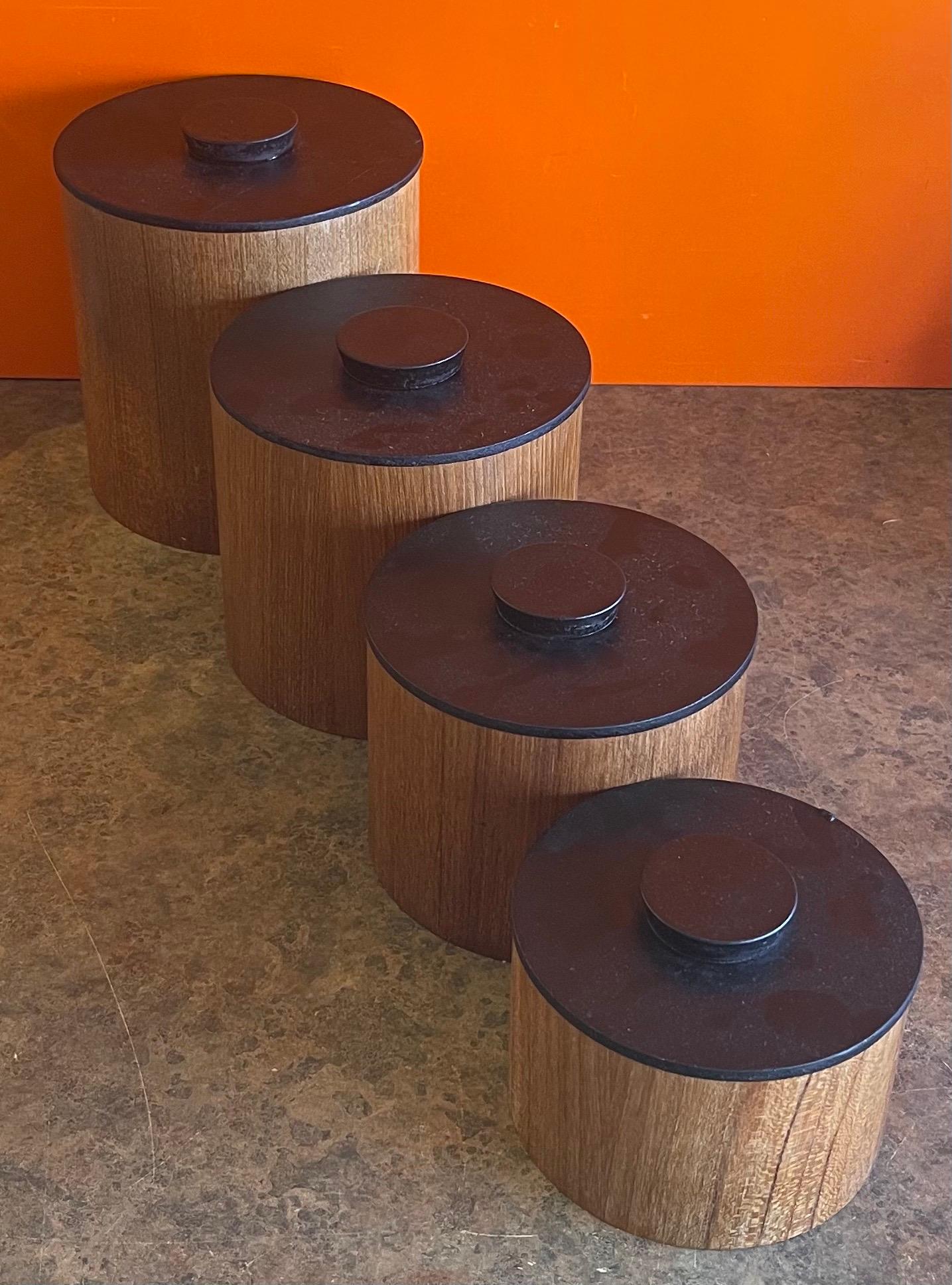 Set of four Danish modern teak stackable storage cannisters, circa 1960s. The cannisters have black painted lids, are in good vintage condition and measure 7