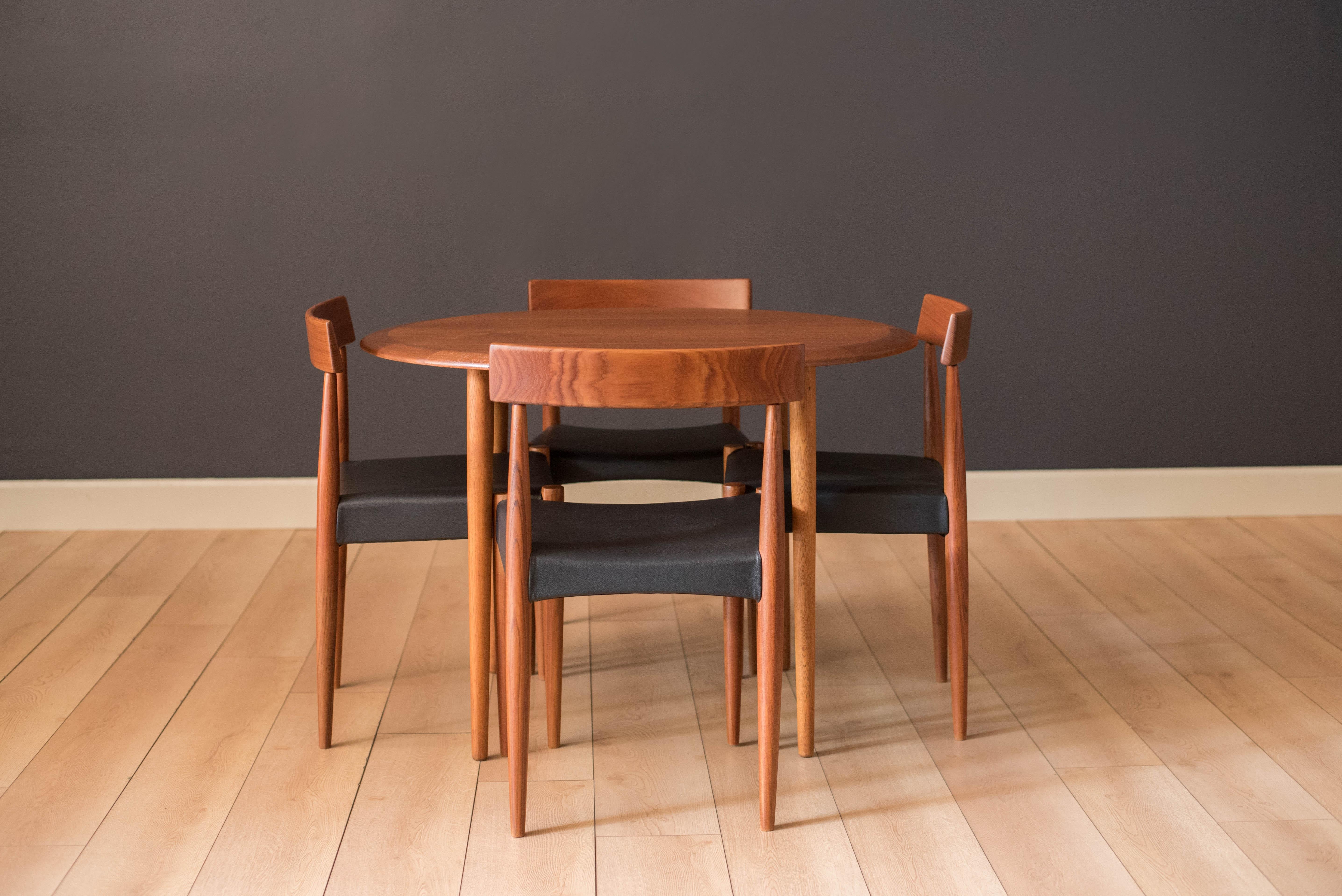 Mid-Century Modern teak dining chairs designed by Arne Hovmand-Olsen for Mogens Kold, Denmark. Each chair features a curved paddle backrest and sculptural supporting legs. This set has been newly reupholstered in black vinyl. Price is for the set of