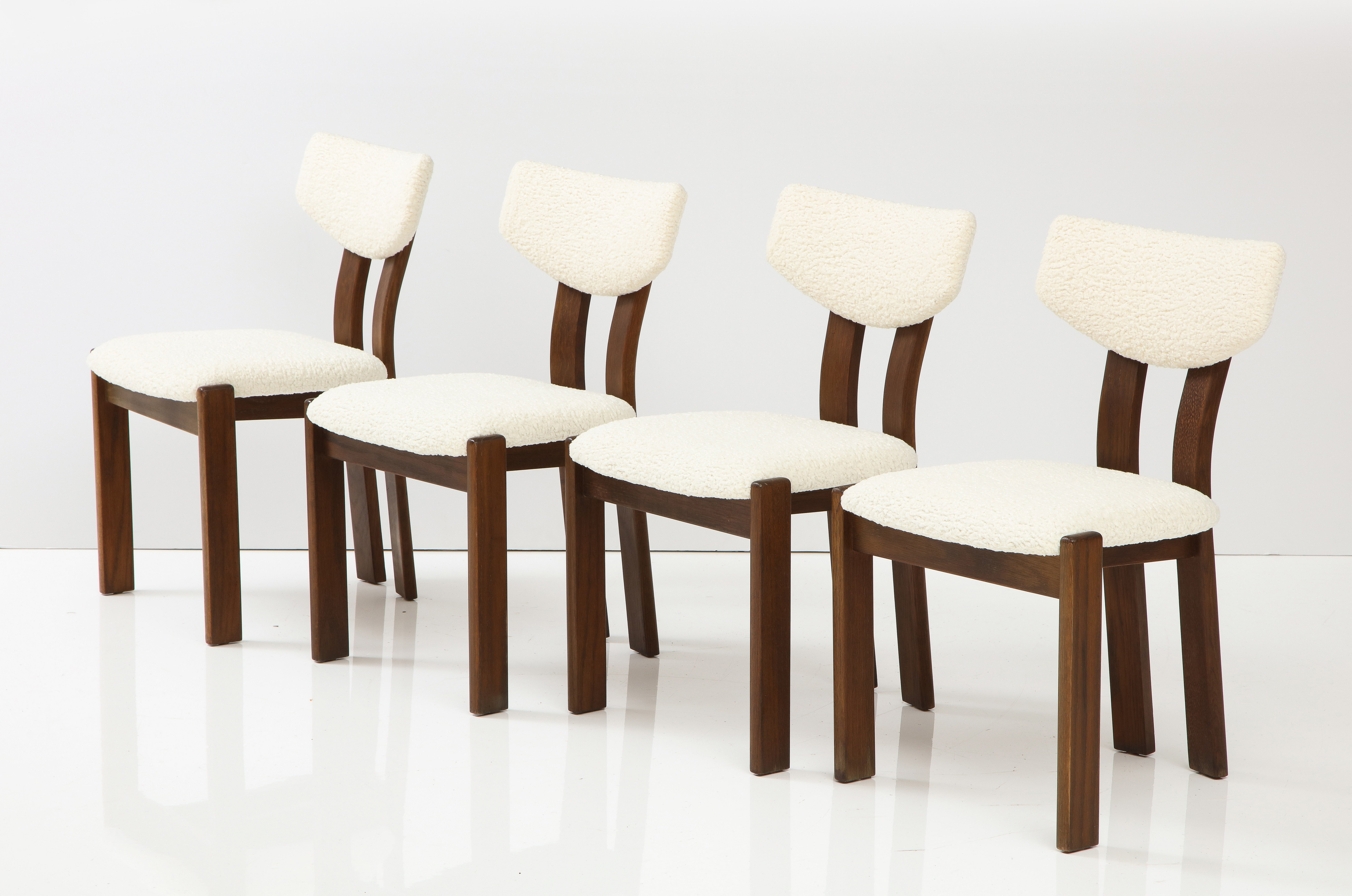 A set of four wonderfully sculpted teak dining chairs with upholstered seats and back rest; newly upholstered in a creamy/white boucle. Extremely versatile, comfortable and chic addition to any interior style. Wonderfully constructed, the chairs are